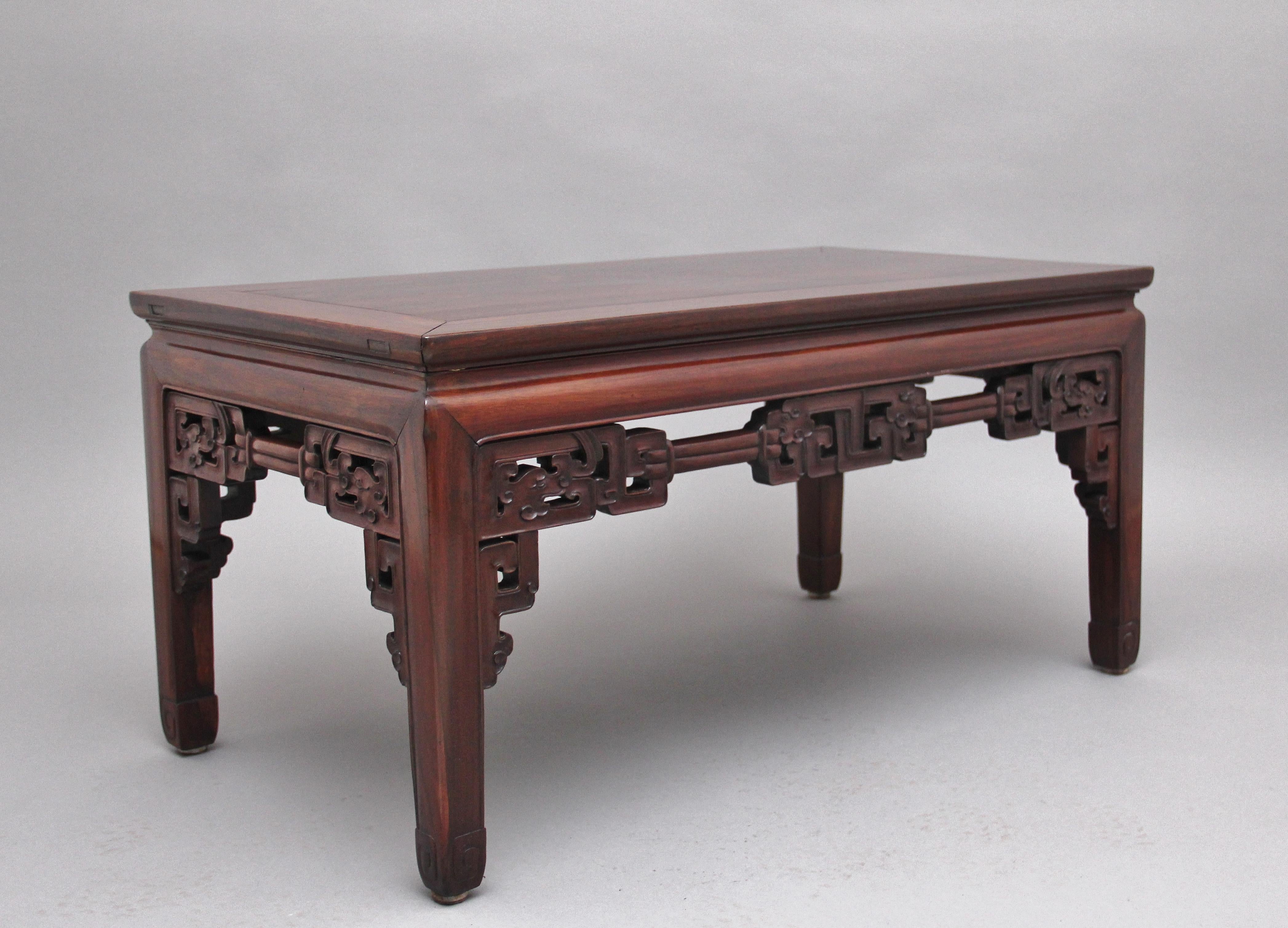 19th century Chinese hardwood coffee table having a nice figured rectangular top supported on square legs ending on carved and scroll feet, all sides decorated with ornate carving in the traditional Chinese style, Circa 1880.