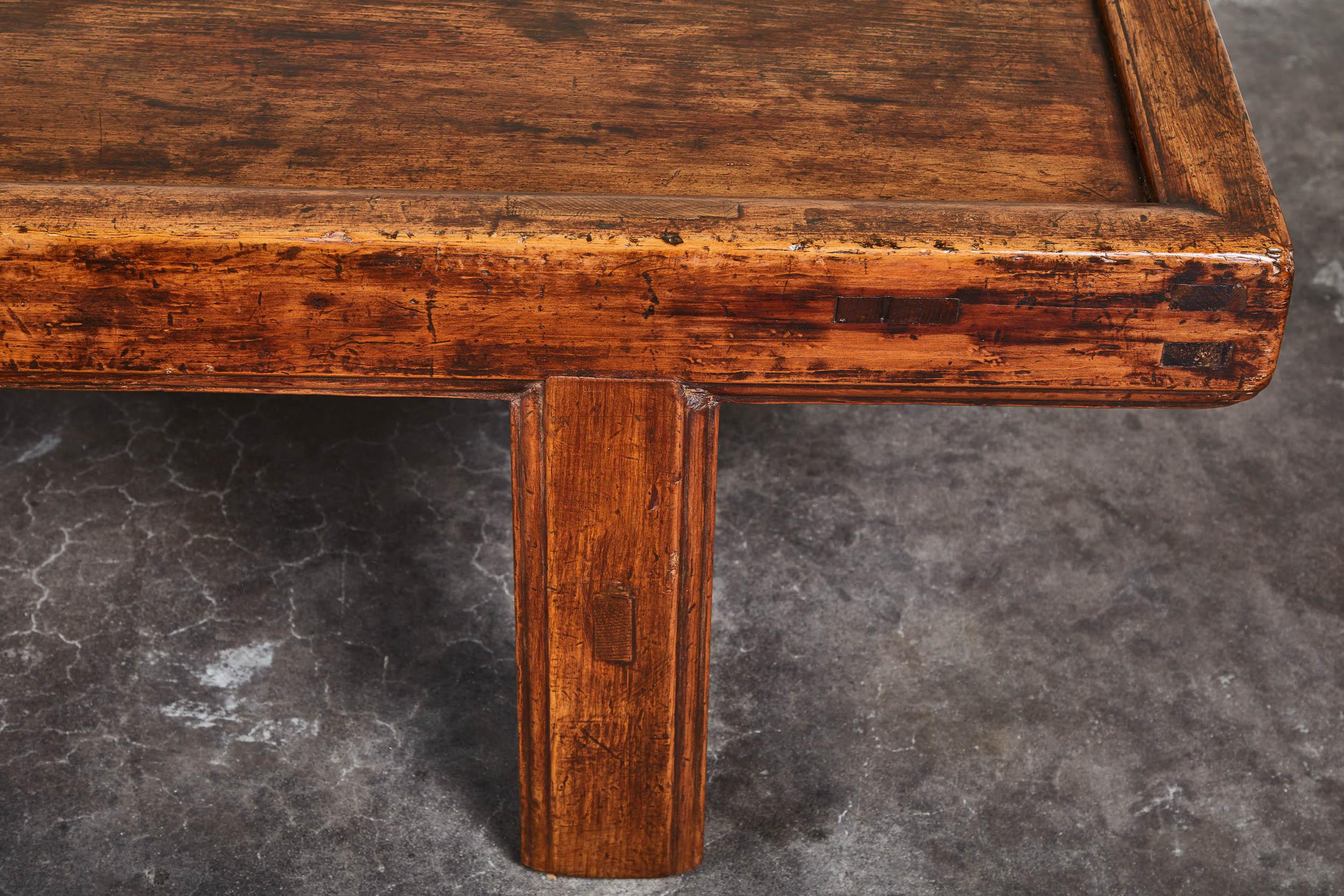 A simple 19th century Chinese low table, with an overall rustic patina. Clean, simple stretchers on four straight legs. Minor cracks and nicks on bottom corners, consistent with age. Top is even in patina and surface. Would make a great textural