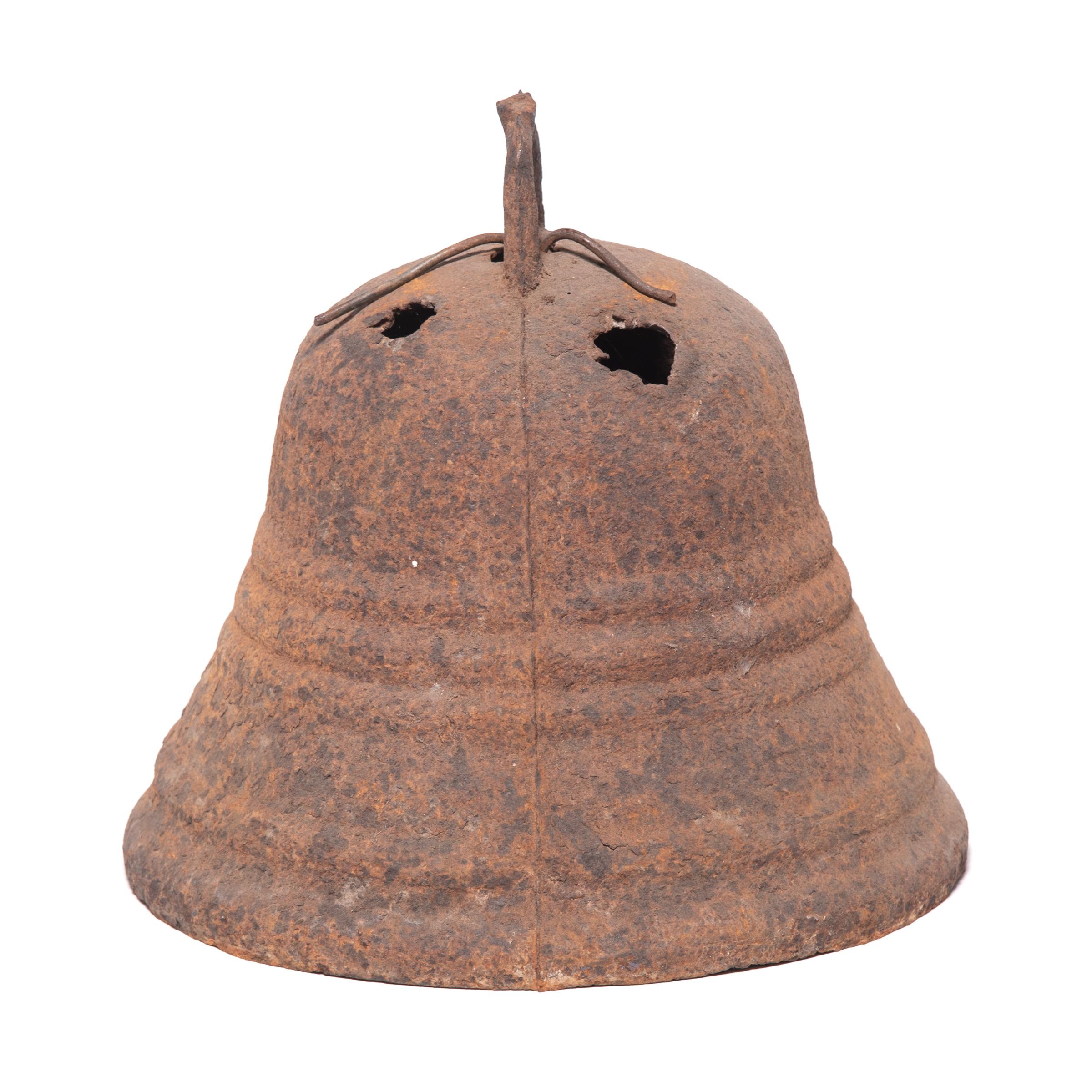 This rustic, 19th century iron bell once pealed in celebration or gave notice of important events in a town in northern China. Complete with its original clapper and marked with holes from being suspended upon a pole, this bell is a delightful