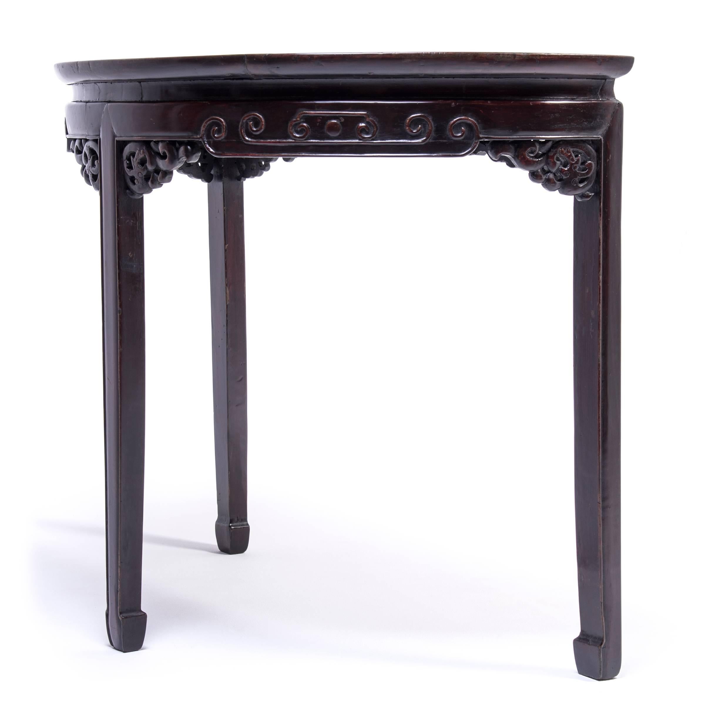 This demilune table is named for its half-moon shape was designed to sit against the wall of a Qing-dynasty home. Crafted from elmwood in the Shanxi region of China, the table apron was finished with beautifully scrolled beading and intricate