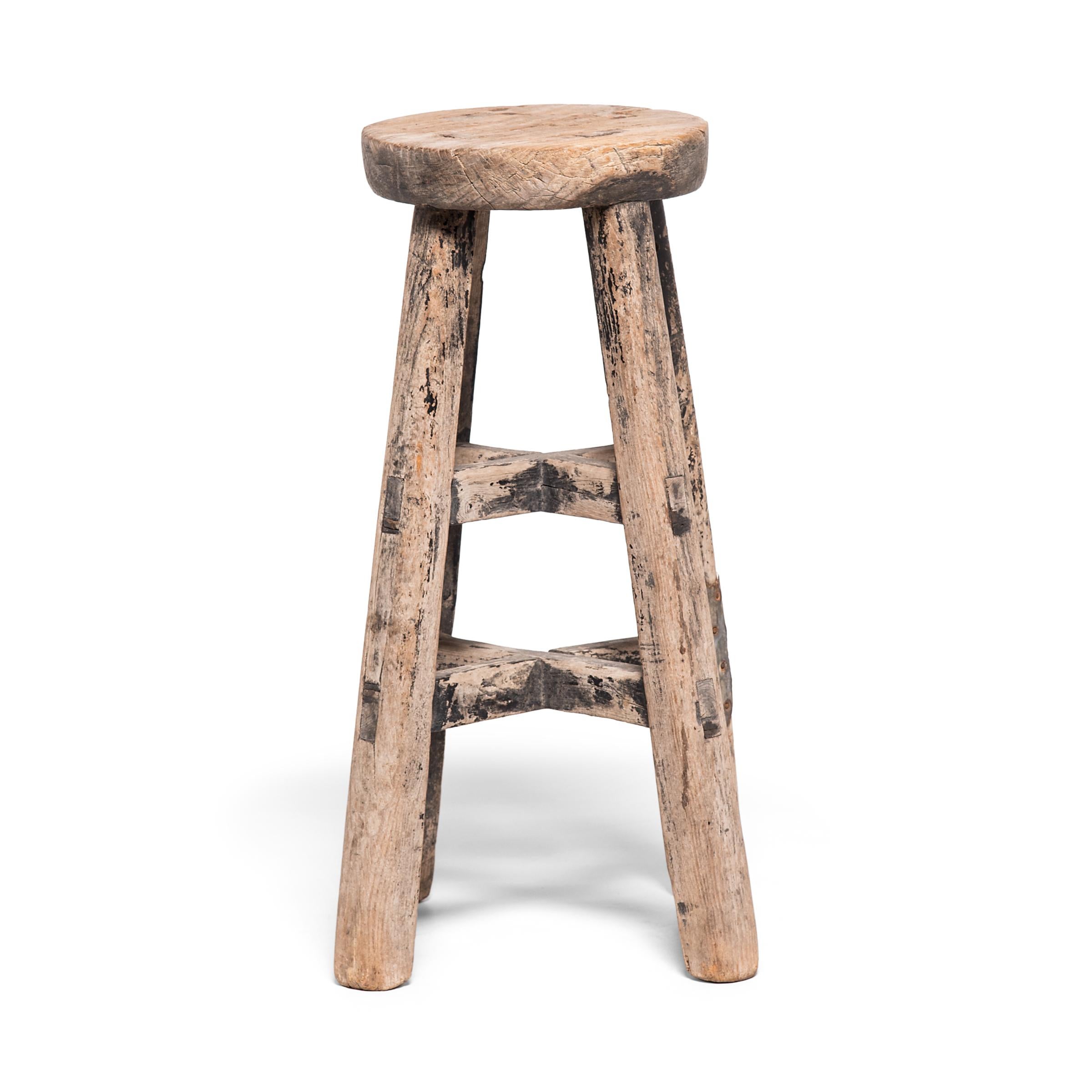 This petite 19th century stool from China's Shanxi province charms with its small scale and complex construction. Crafted with traditional mortise-and-tenon joinery techniques, the stool features four legs and two sets of interlocking stretchers,