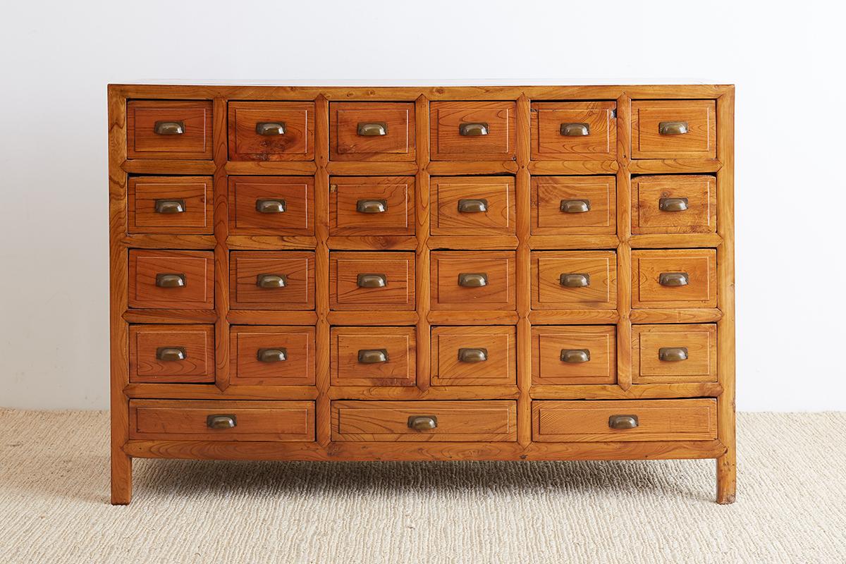Impressive 19th century Chinese Elm apothecary cabinet or chest. Features 27 carved drawers with each small drawer divided into 2 sections inside. The drawer fronts feature later brass shaped pulls. The chest was constructed using mortise and tenon