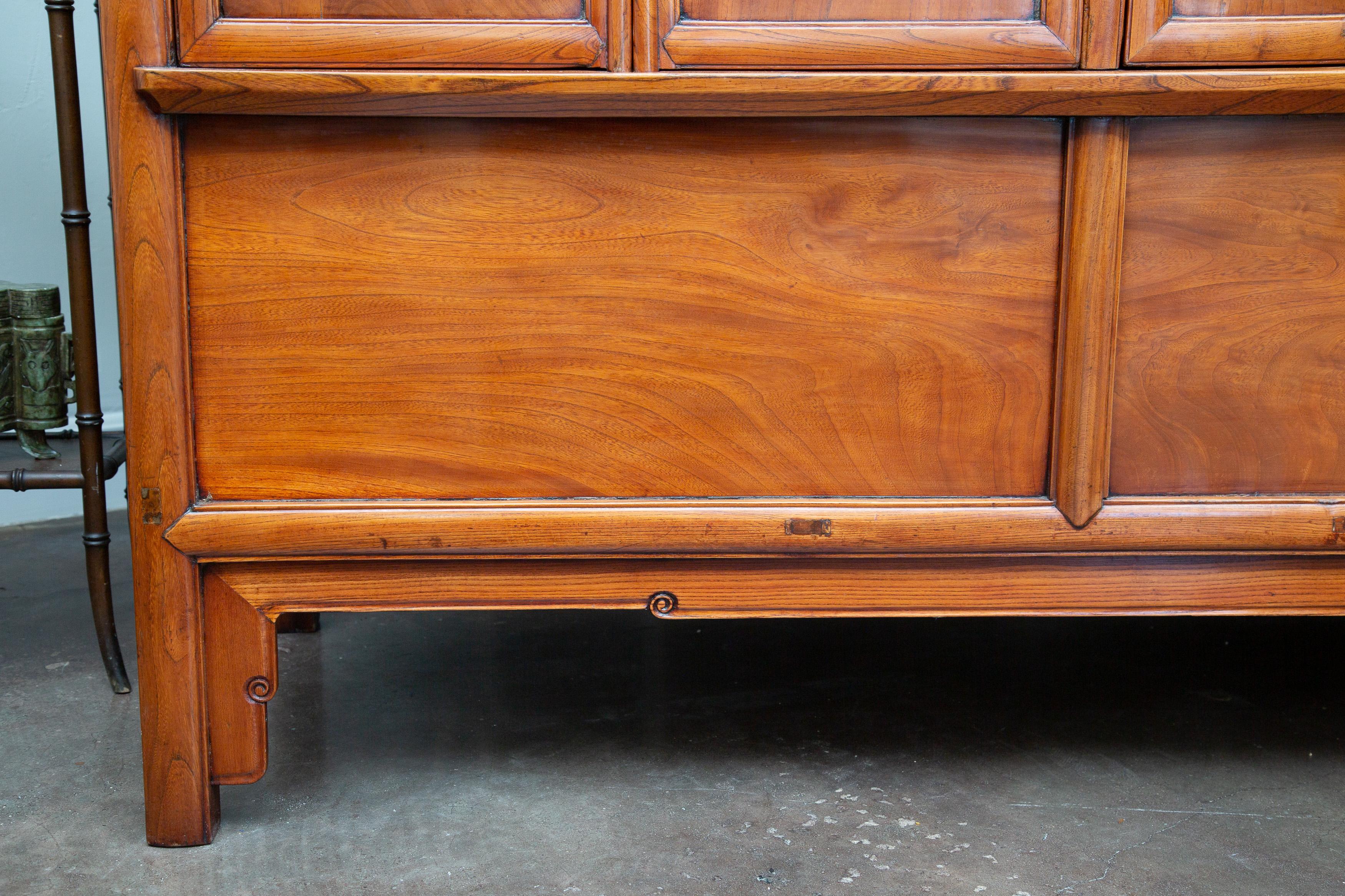 This is an imposing Chinese elm cabinet, with a warm, mellow welcoming patina, contradicting its size. The cabinet contains four long, narrow doors that open to reveal shelving and drawers.