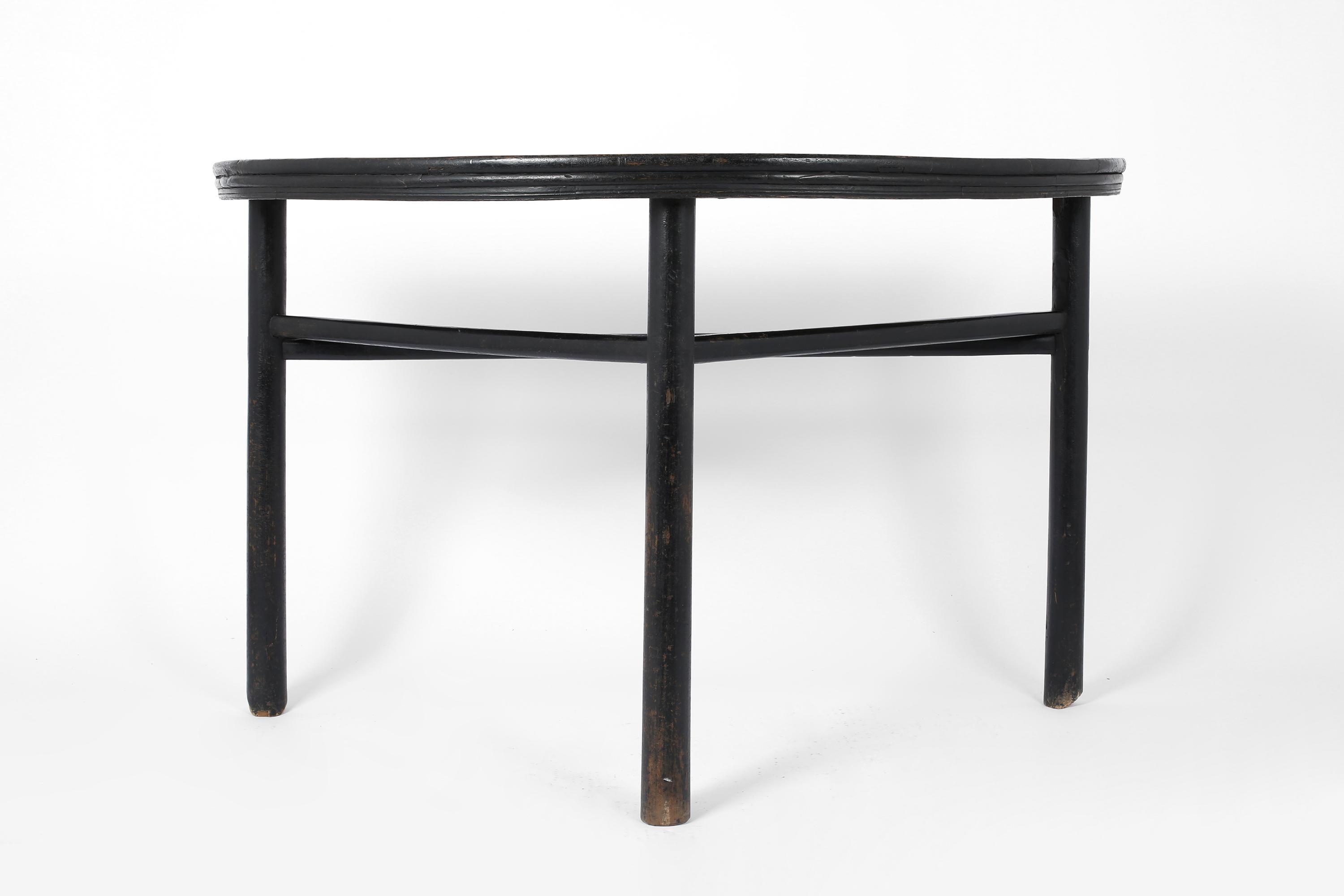 A 19th century demi-lune console or lamp table, constructed from elm with it’s original worn black lacquer finish. Featuring almost modernist, cylindrical legs and offset stretchers, with exposed tenon joints and moulded edge. Chinese, c. 1880.