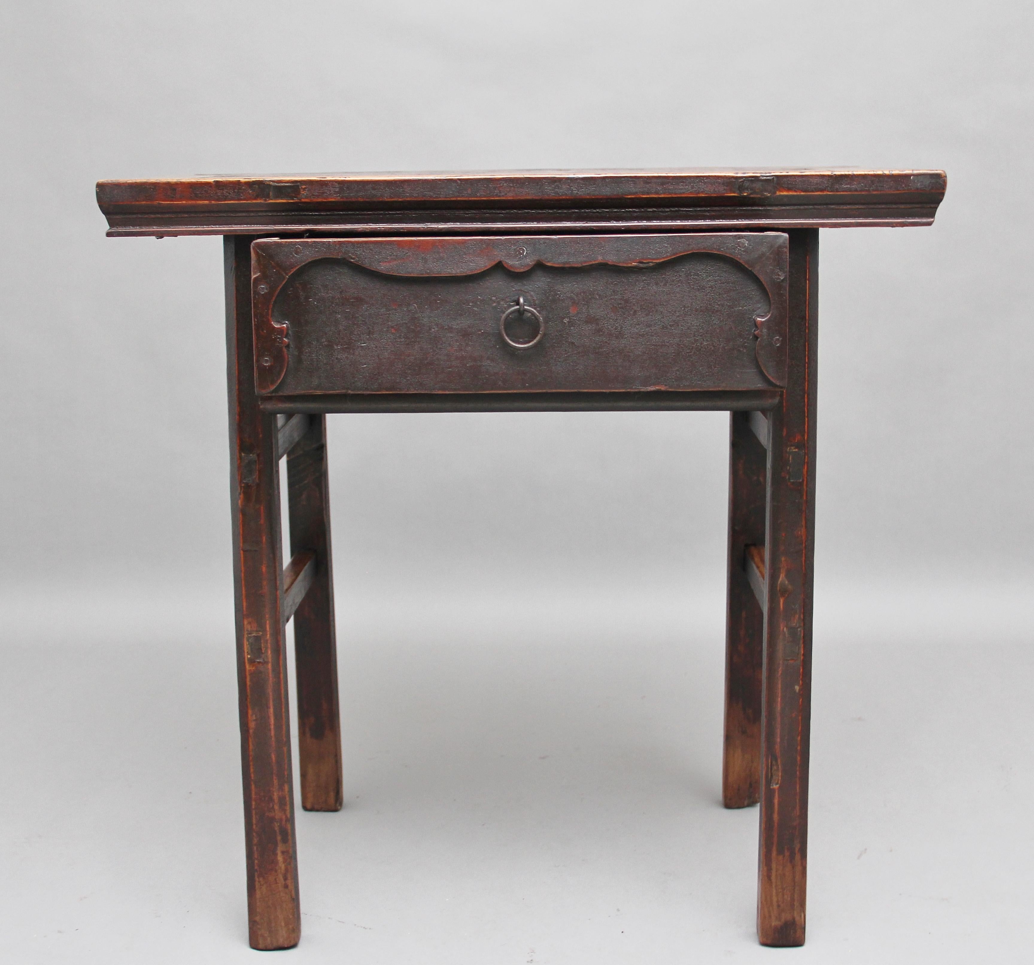 19th century Chinese elm side table, the rectangular top above a single drawer with carved decoration on the drawer front with original brass ring handle, standing on square legs united with side stretchers, circa 1880.