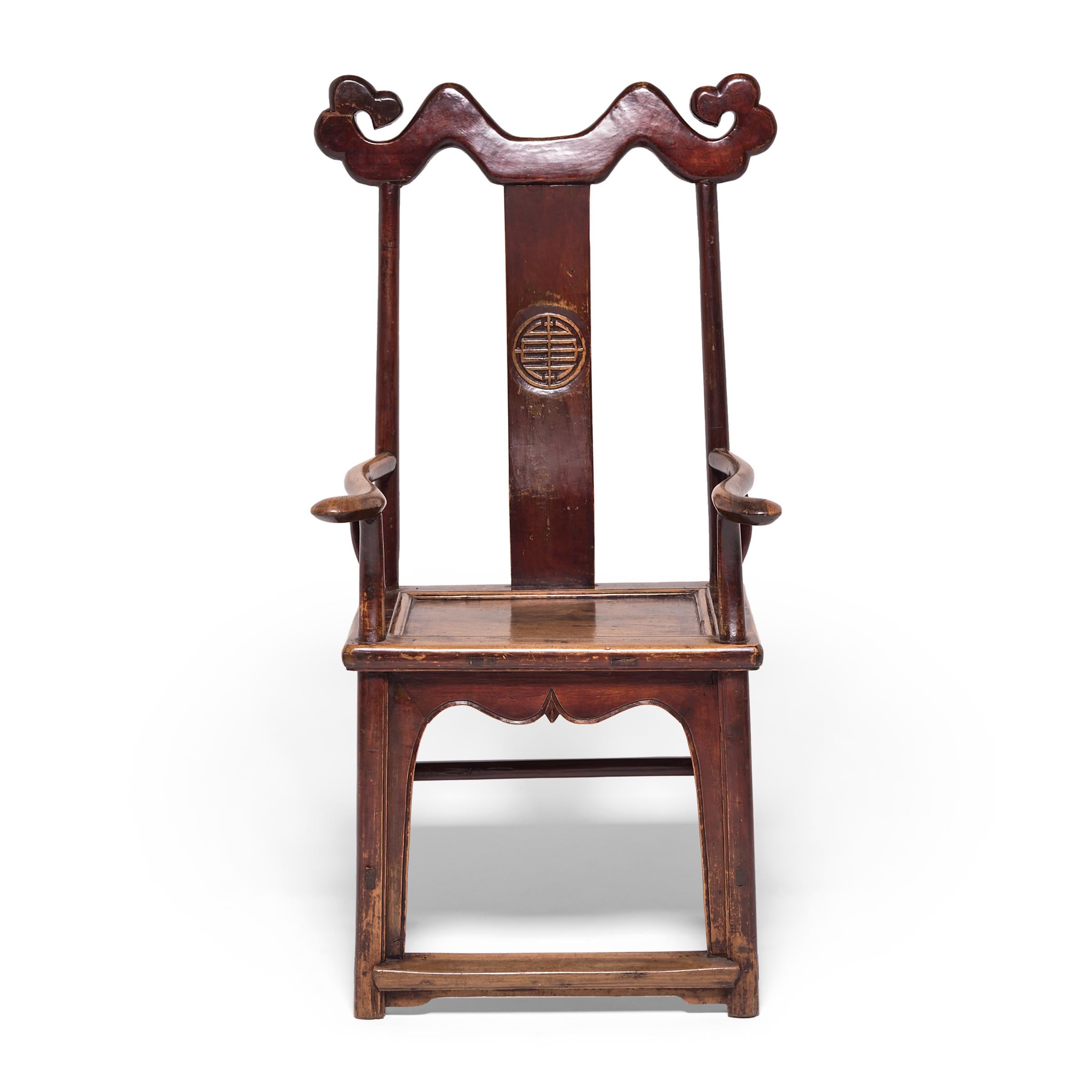 This 19th-century Emperor-style chair features an exaggerated cloud-motif crest rail and a backsplat carved with the Shou character, a symbol of longevity. The grand chair's smoothly worn and deeply patinated surface reveals the many centuries of