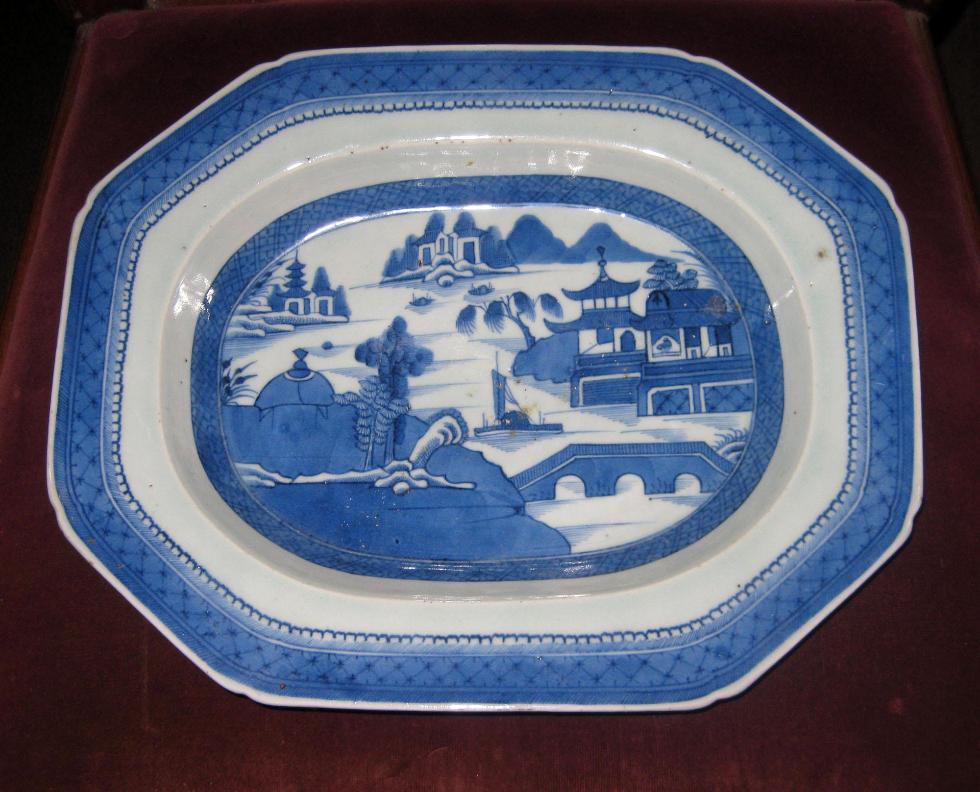 Canton deep octagonal shaped platter decorated in an under-glazed blue with a traditional Chinese hand decoration set against a white porcelain ground. The bottom rim of the platter is unglazed.
Canton porcelain was manufactured and fired in the