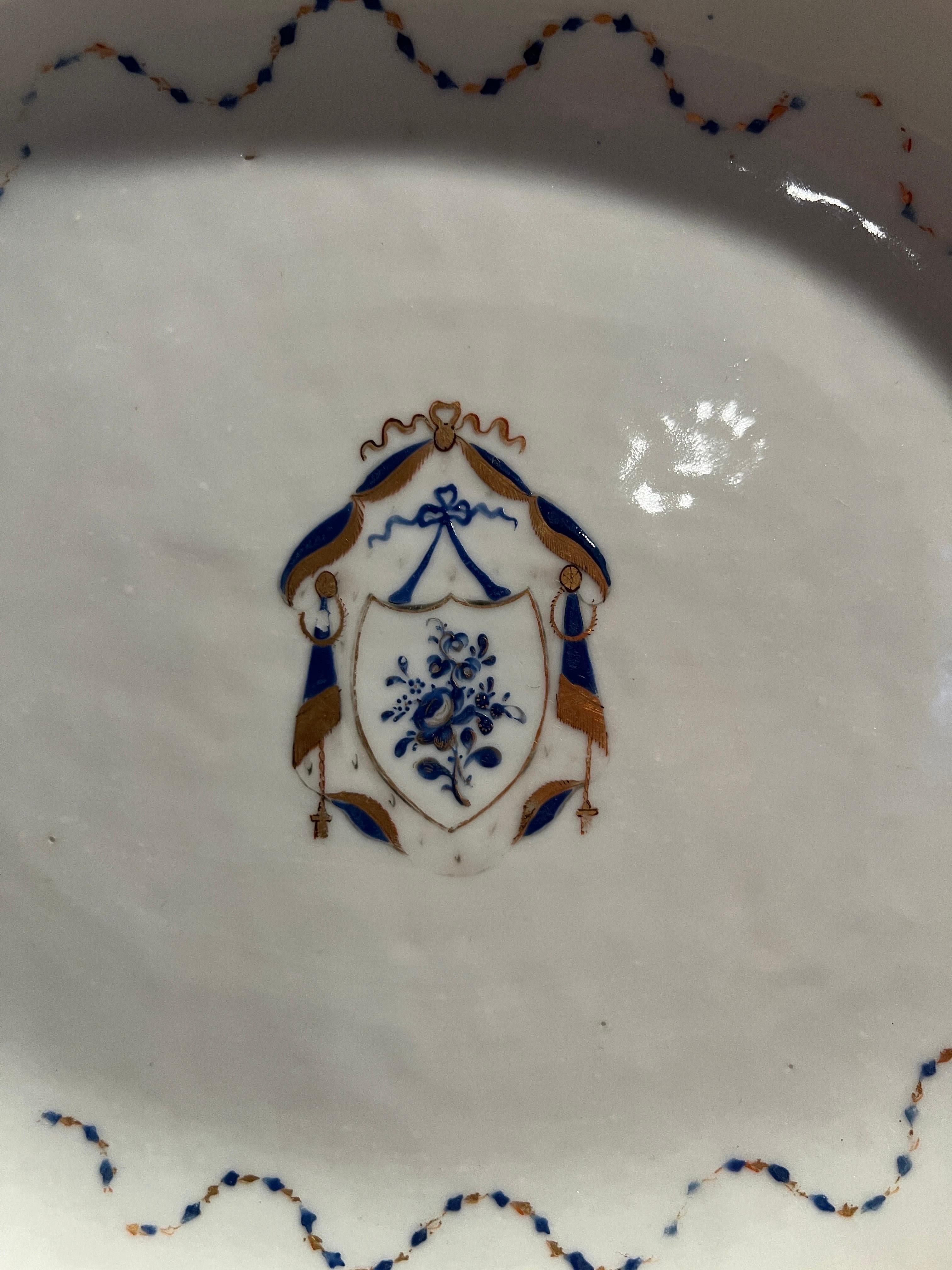 Chinese Export, late 18th to early 19th century.

An antique porcelain platter with a blue enameled edge, chestnut basket piercing between edge and recession, a gold and blue intertwining ribbon surrounding a wonderful central armorial medallion.