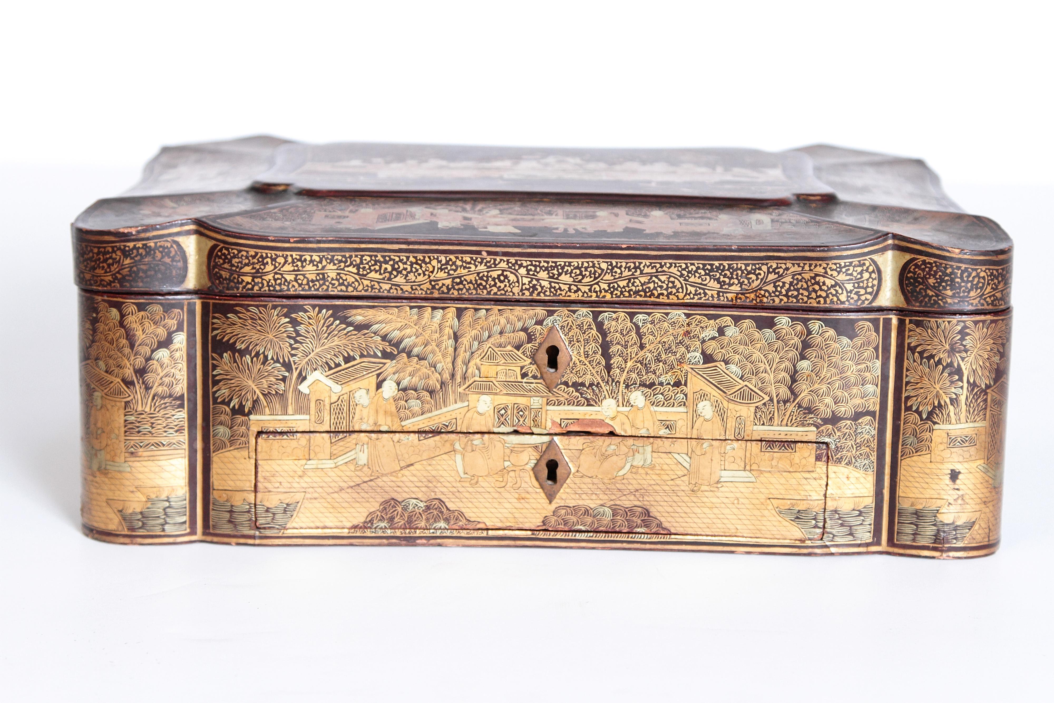A beautifully executed black lacquer sewing box made for the English market. The rectangular shaped box has gilt chinoiserie overall with handles and a scalloped paneled lid. Fitted interior with bone pieces intact.