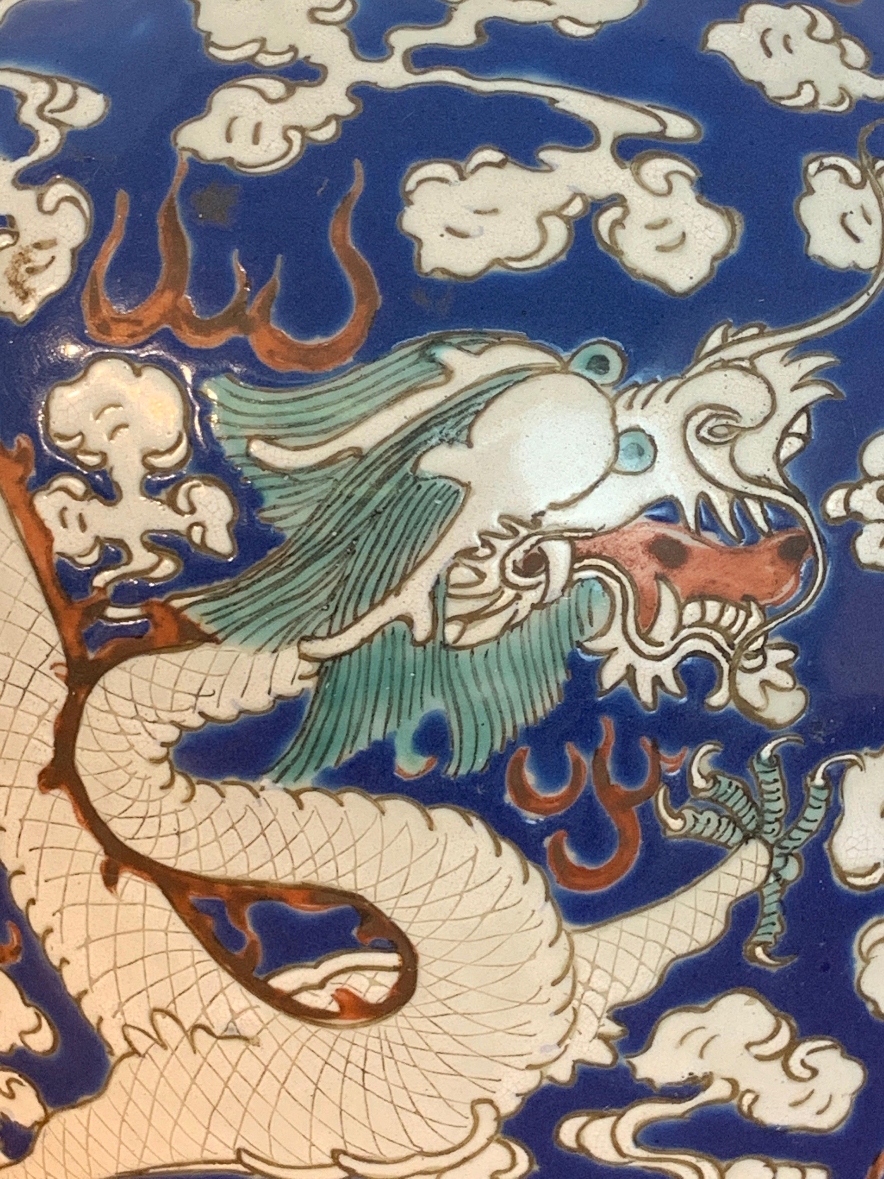 20th century Chinese Export Polychrome enamel ginger jar with carved wood lid and base, with a primarily blue background with Imperial floating dragon, with teal waves at bottom. Unmarked, complete with carved pierced lid with hardwood base
Jar