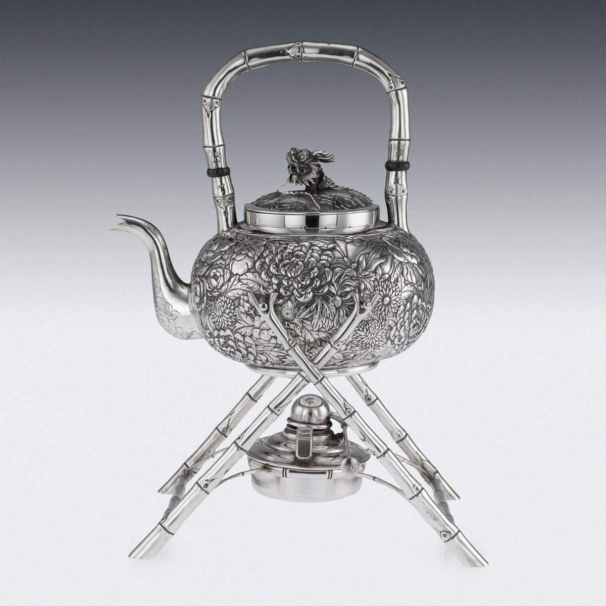 Antique late 19th century Chinese export solid silver tea kettle on stand, the body chased in relief with floral decoration, the domed lids mounted with a dragons head and chased in a complimentary style. The kettle is suspended on a stylized, well