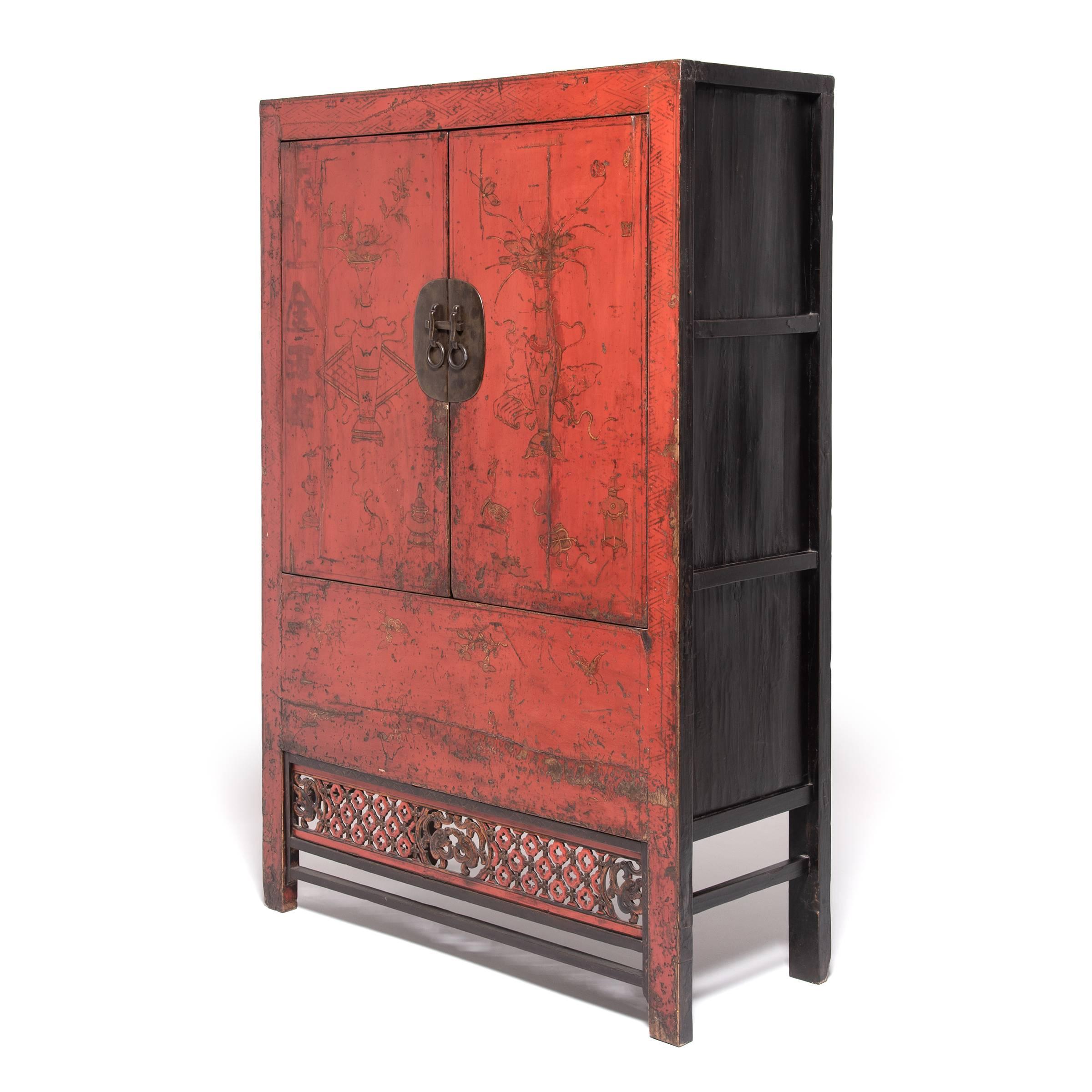 This red lacquer cabinet is an excellent example of the rich, decorative style of cabinetry built during the 19th century in China's Shanxi province. Traces of the original gilt paintings depicting vases with auspicious flowers remain. The