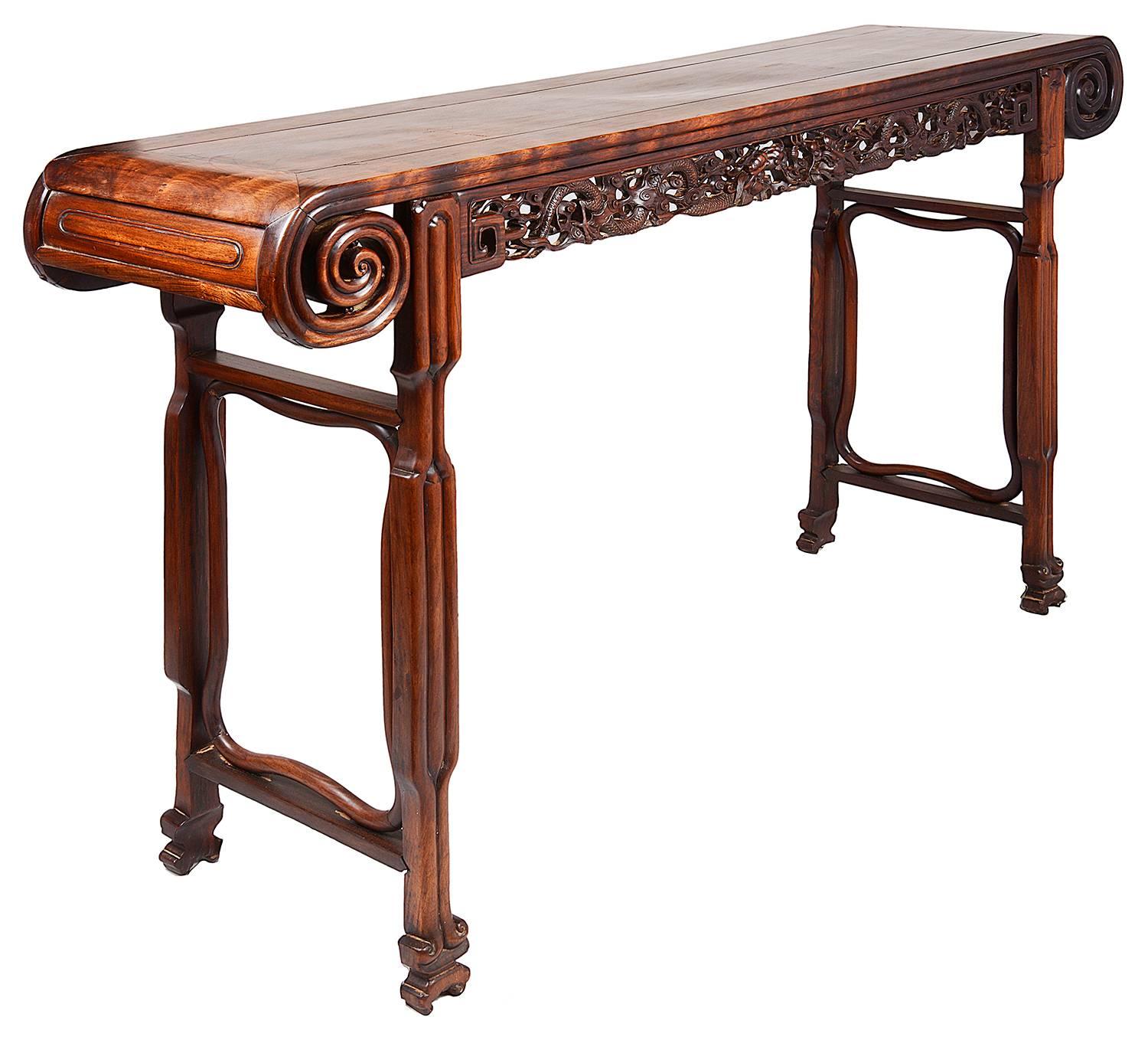 A good quality late 19th century Chinese hardwood alter table, having three inset panelled top, carved scrolling ends, the frieze with carved mythical dragons. End supports each with stretchers and terminating in scrolling carved feet.
