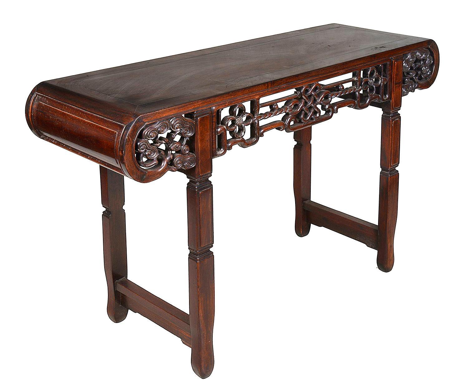 A very good quality 19th Century Chinese hardwood Alter table, having inset panels to the top and scrolling ends, hand carved and pierced ribbon and scrolling foliate decoration to the frieze, raised on square section legs united by stretchers,