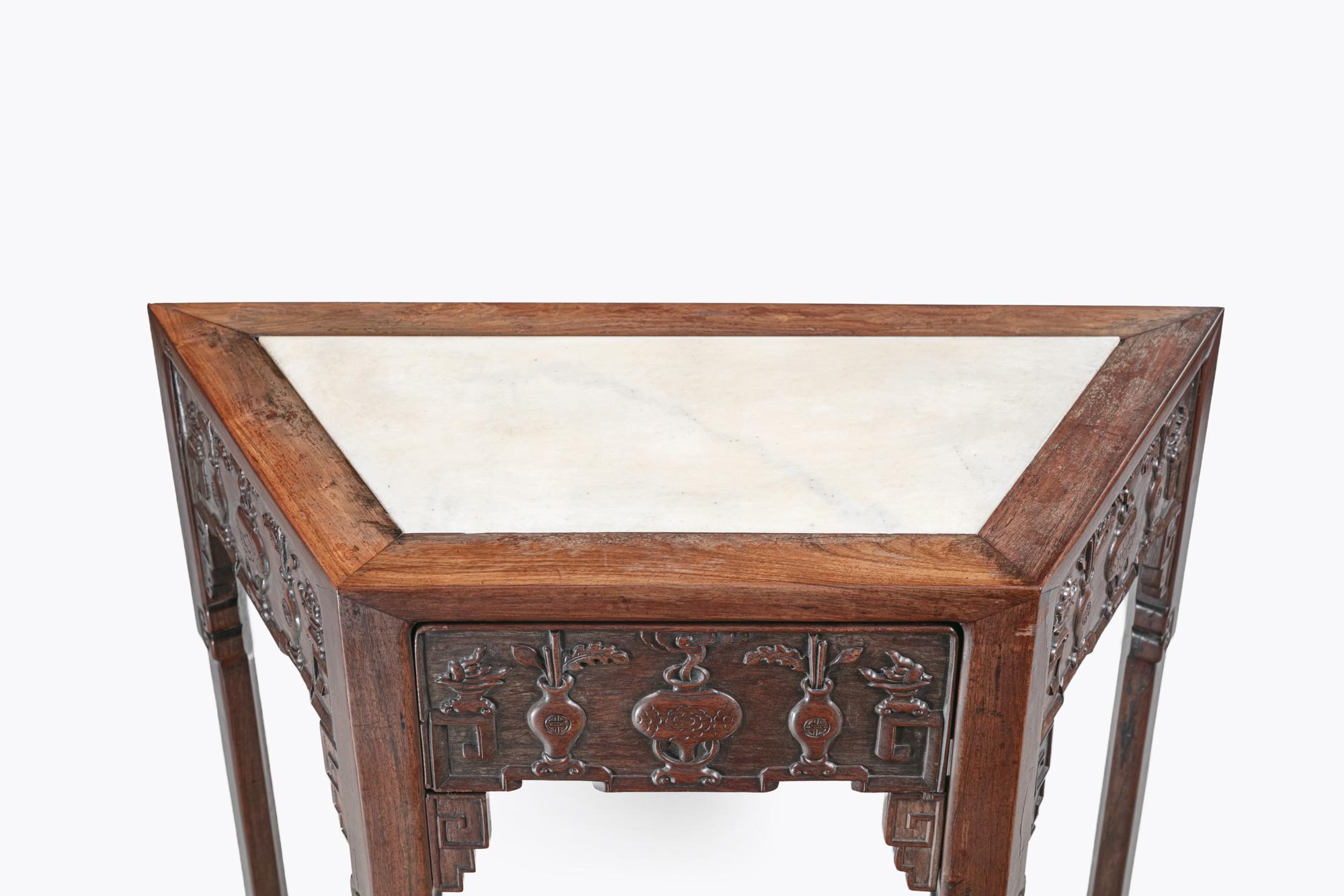 Table d'autel chinoise du XIXe siècle en bois de hong mu, de forme trapézoïdale inhabituelle, avec un plateau en marbre et une frise minutieusement sculptée, présentant un tiroir avec des urnes et des feuillages sculptés. Les pieds se terminent par