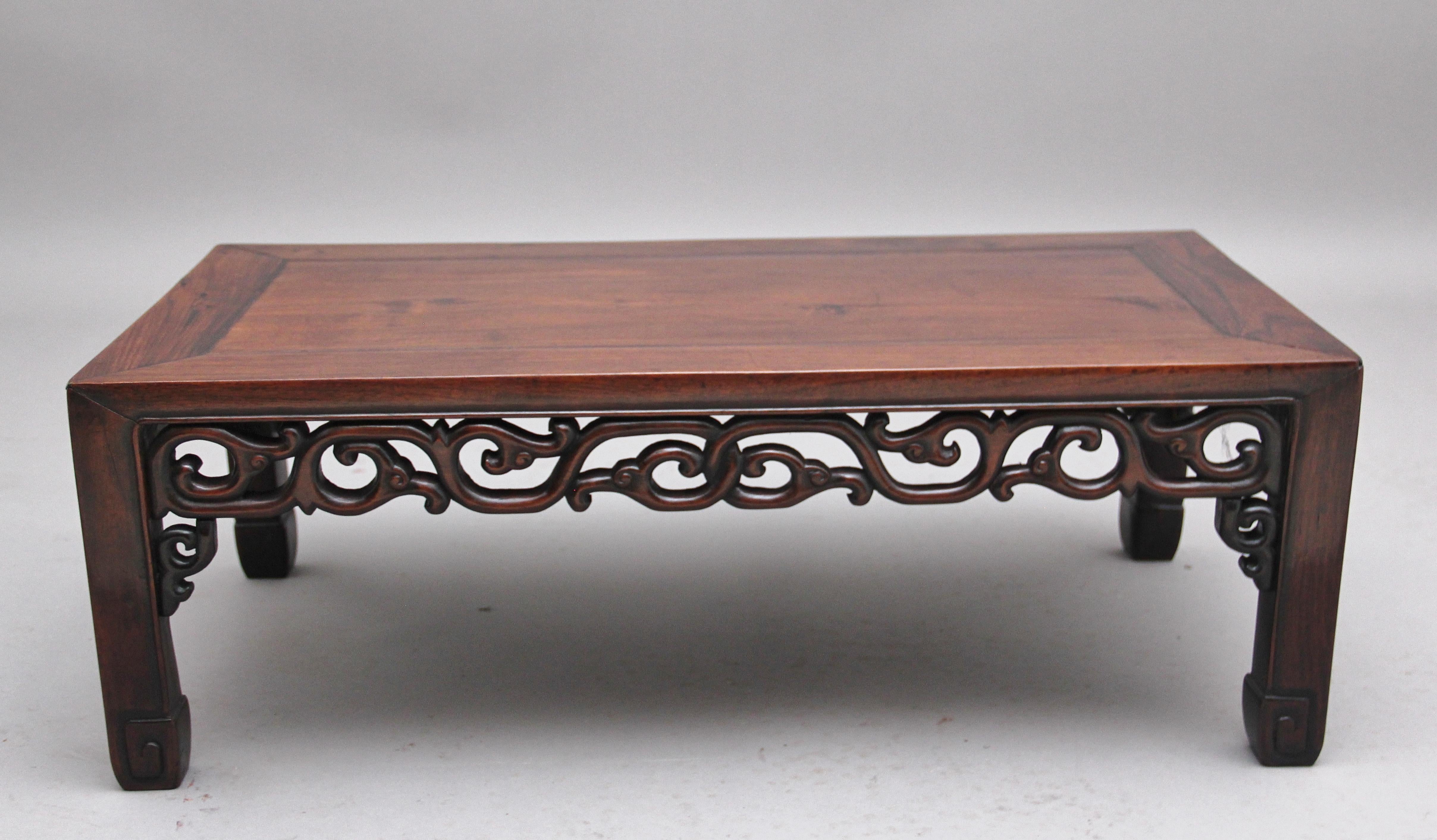 19th century Chinese hongmu low coffee table having a nice figured rectangular top supported on square legs ending on carved and scroll feet, all sides decorated with ornate carving in the traditional Chinese style. Circa 1880.
 