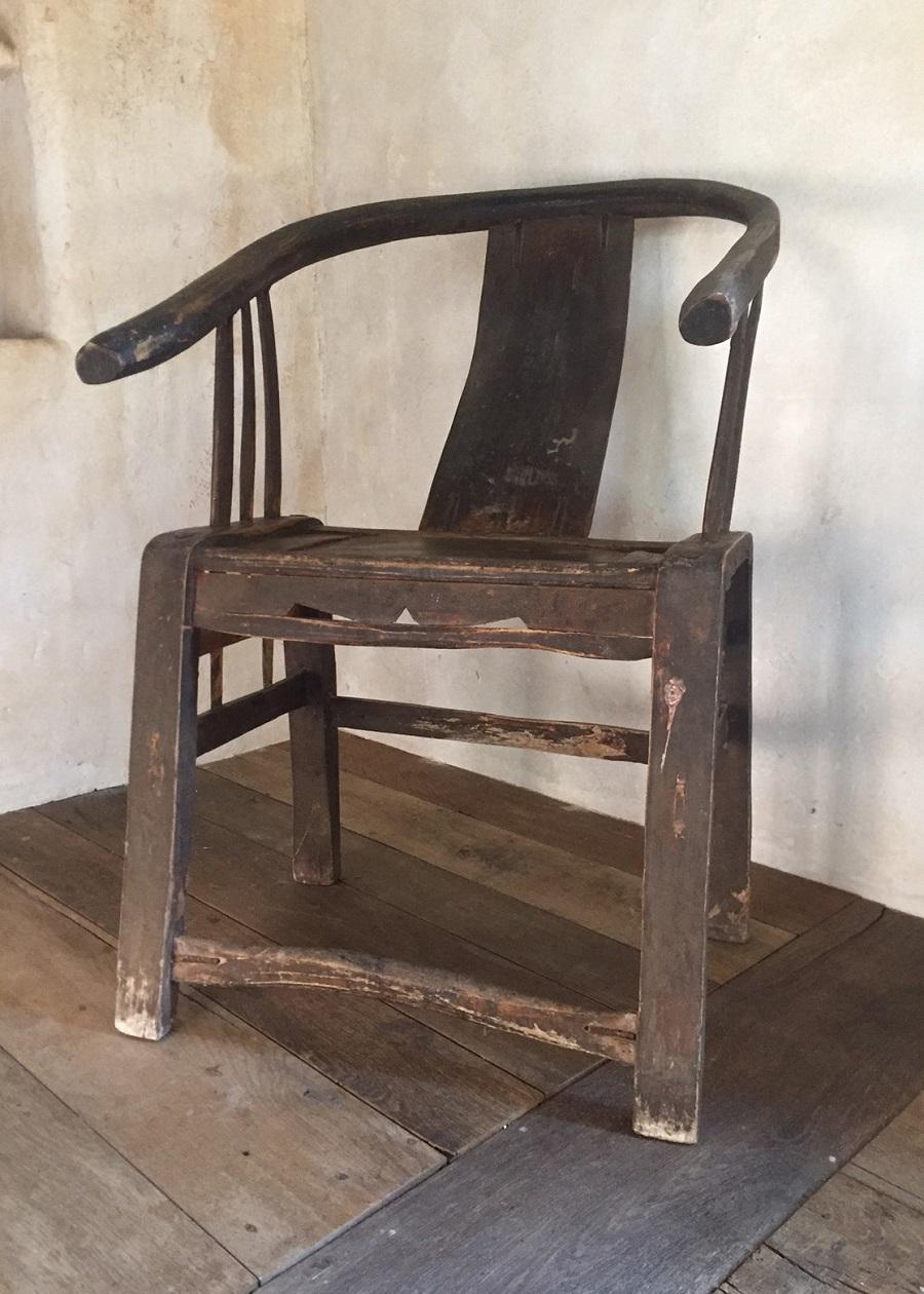 A primitive 19th century elm horseshoe back armchair. This classical Chinese armchair has good proportions and a nice patina. The original black lacquer is softly faded and crackled. It is very sturdy and ready for everyday use.