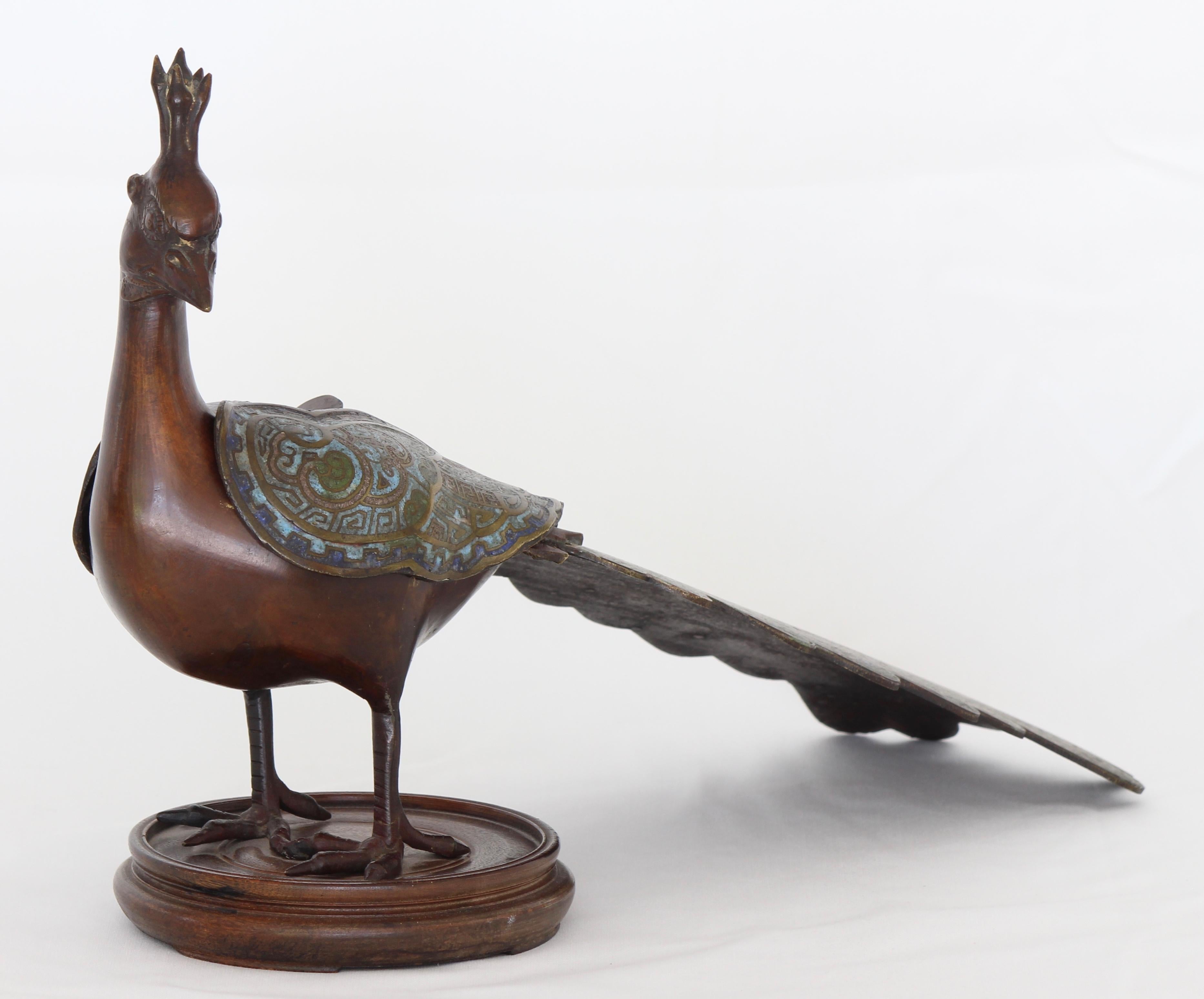 A large and elegant early 20th century enamel and bronze peacock form incense burner or censer. The bird is mounted on a later weighted wood base.