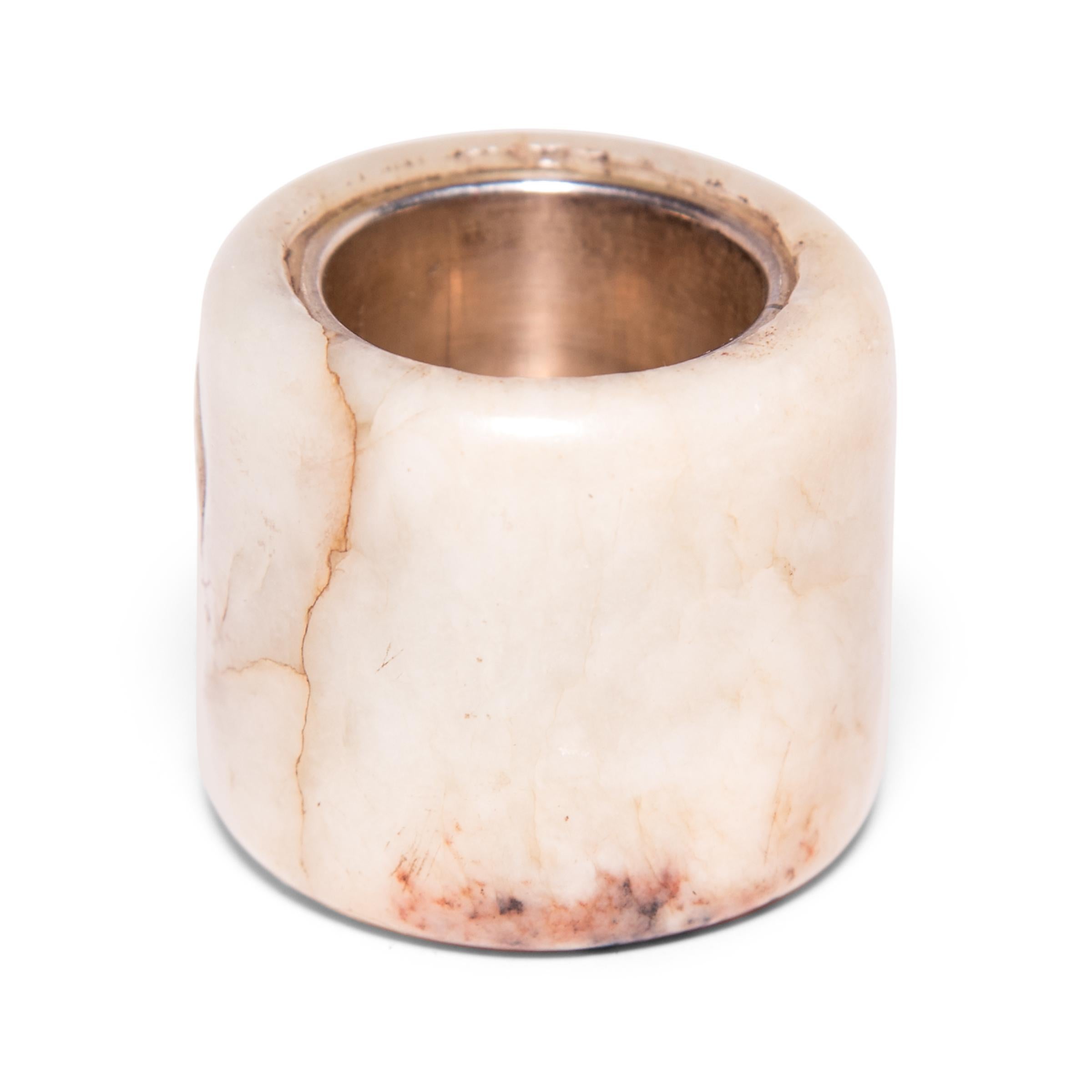 Hand carved of milky white jade, this 19th century Archer's ring was likely once worn by a gentleman-scholar in northern China. Traditionally, Chinese archers wore these rings to protect their thumbs while drawing a bowstring. Over time, these jade