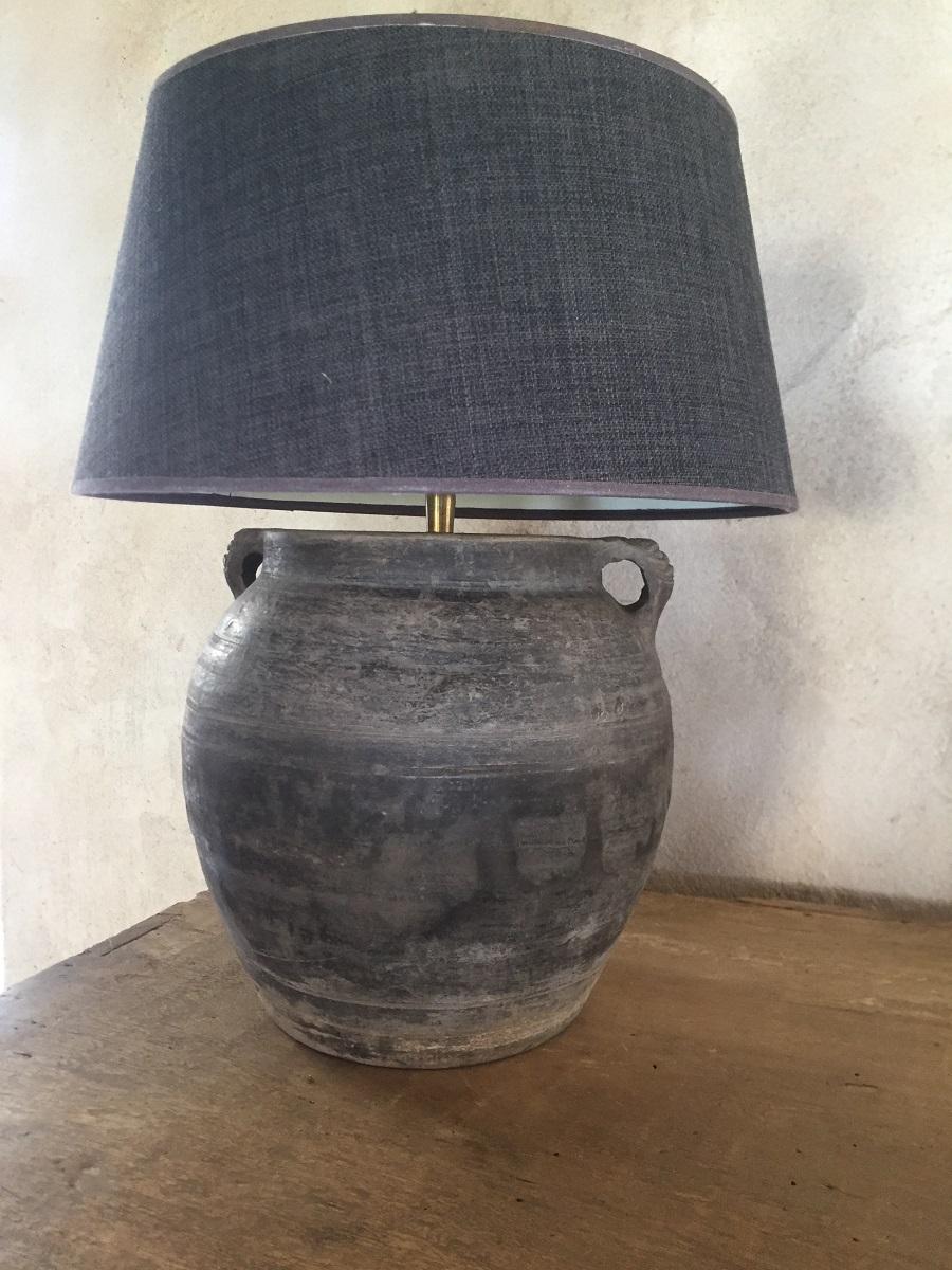 A Chinese earthenware jar turned in to a table lamp. The jar is of a typical design made in the 19th century from grey clay. It is subtly incised and decorated with a subtle patina.