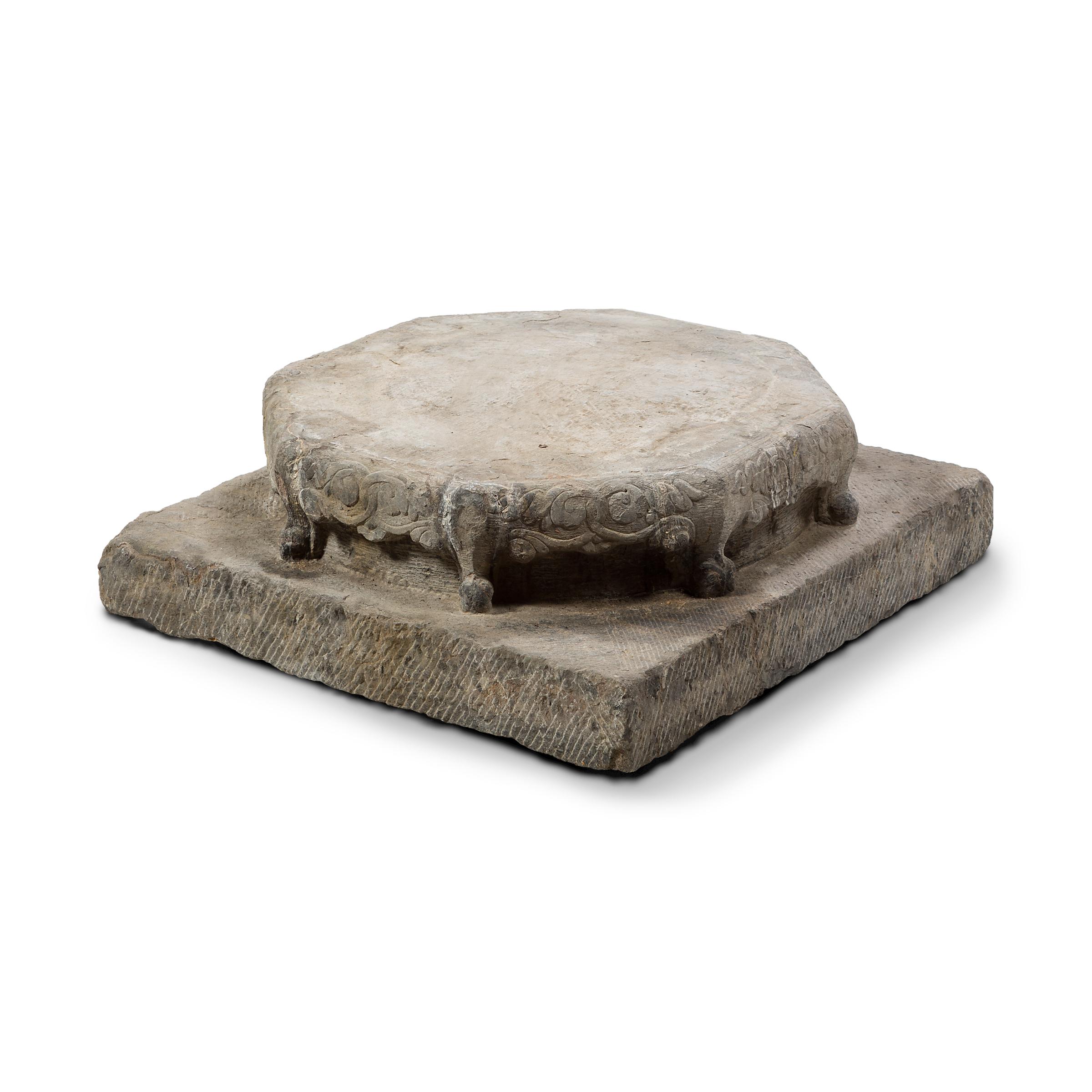 This 19th-century column base likely figured into the imposing surroundings of a Qing-dynasty courtyard, supporting a tall wooden beam as part of a grand entryway. Atop a square slab patterned with hash marks, sits an eight-sided base, carved with