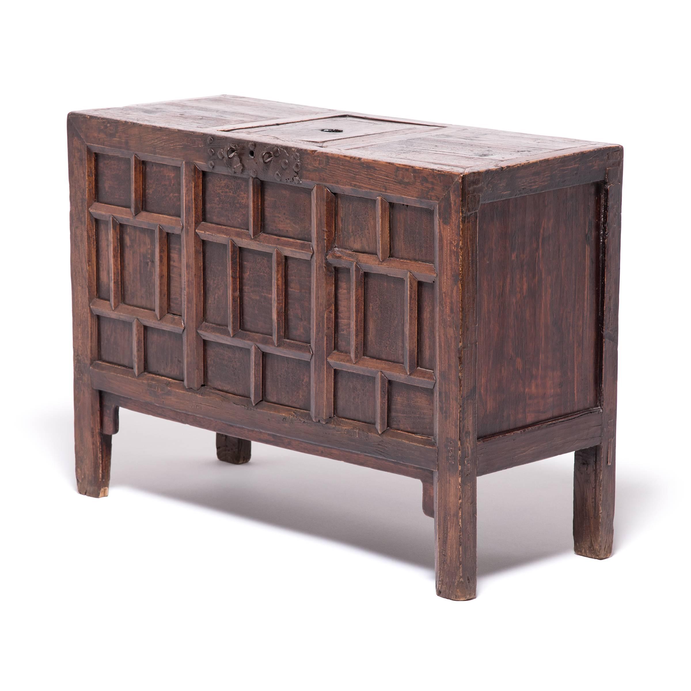 This 19th century chest from Northern China was designed as a large bank to collect and hold monetary savings. The slot in the removable board on the top allows coins to be inserted and later removed by lifting the board. The carved multi-paneled