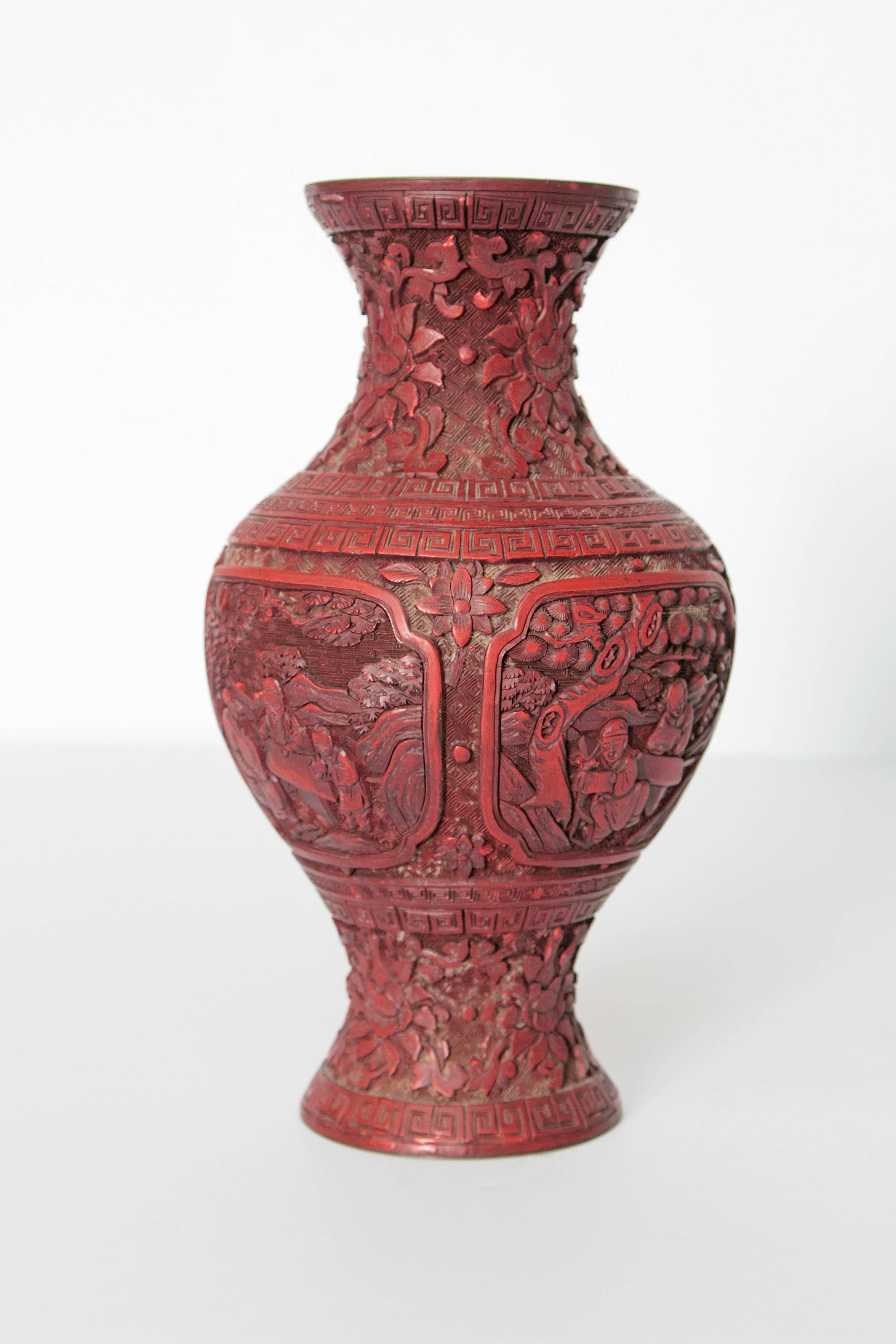 A Chinese lacquer cinnabar vase. Panels with people, Greek key design and floral carvings.