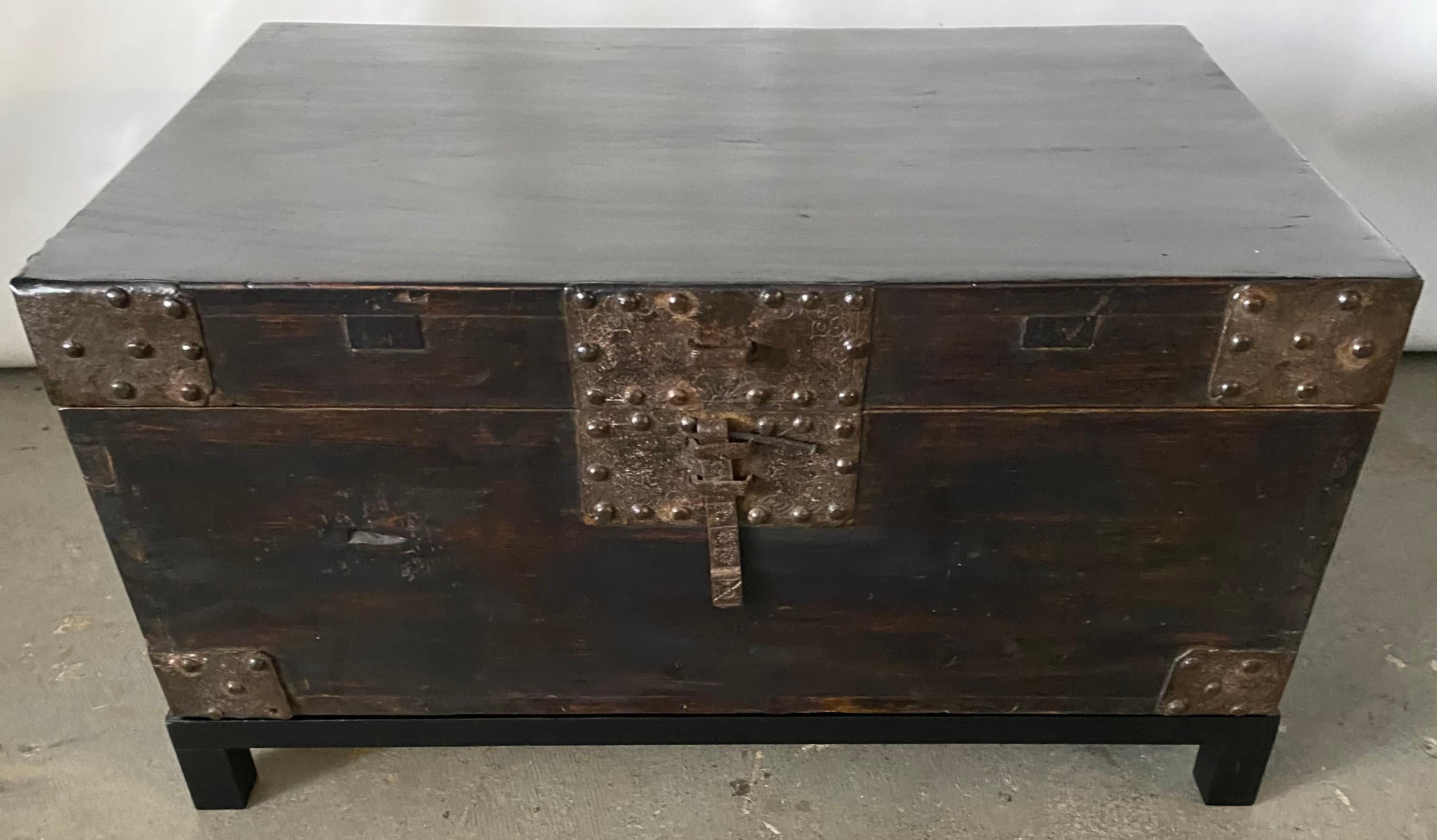 A very handsome Chinese lacquered trunk or coffee table with exceptional heavily embellished hand-hammered hardware -- iron handles, hinges, corner plates and lock which uses a cross piece or lock (not included) to secure the flat bolt. The chest is
