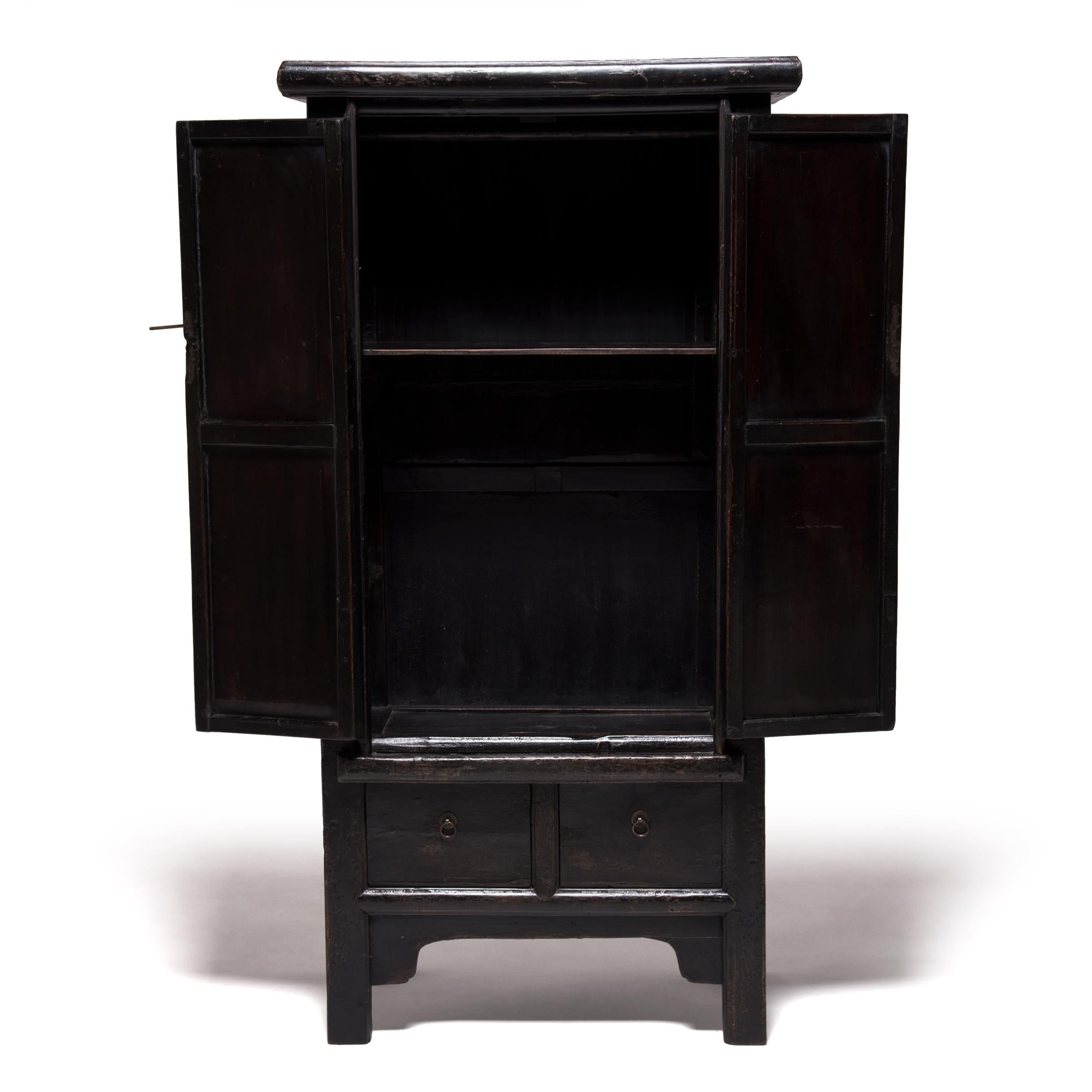 This mid-19th century two door cabinet from China's Hebei province is still coated in a lustrous black lacquer finish after nearly two centuries of use. A laborious process, lacquer must be applied slowly, brushed on in long fluid motions. A