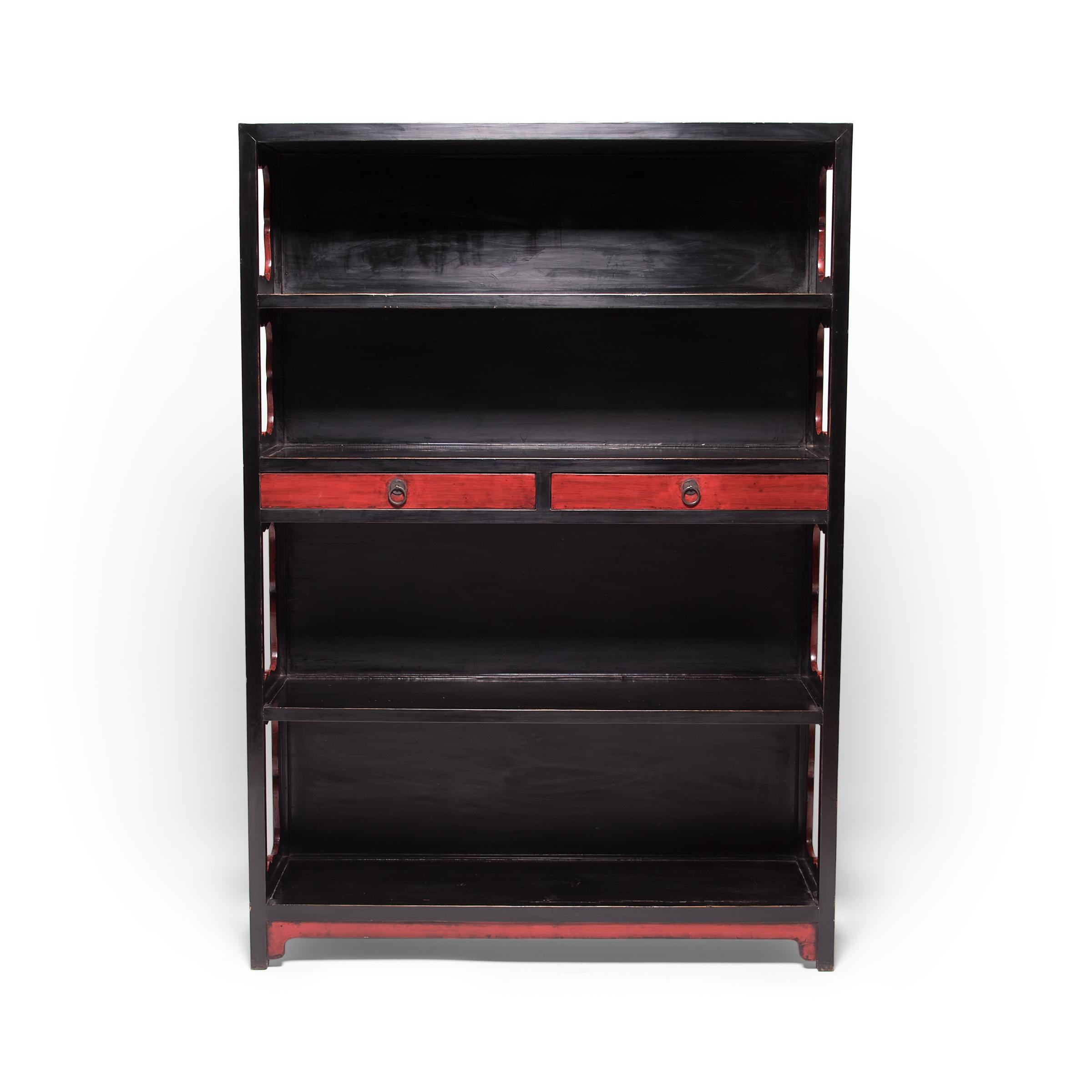 This striking red and black lacquer bookcase once stood in the center of a traditional Chinese scholars' studio, displaying a collection of books, scrolls, and treasured objects. The elegant case has two shallow drawers and four open shelves, each