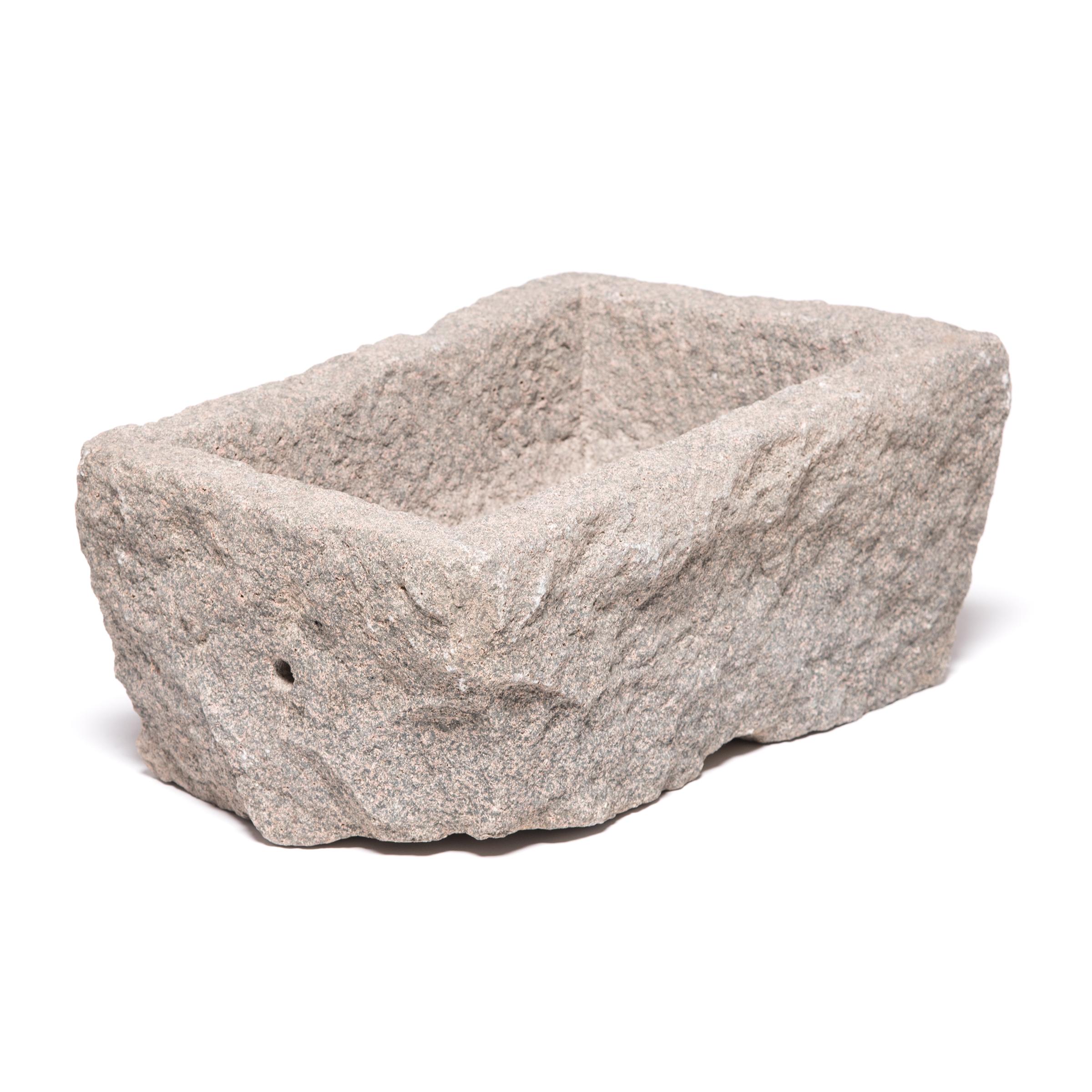 Once a common sight in courtyards throughout rural China, this textured stone trough was filled with grain for chickens and other barnyard fowl. Chiseled from a block of stone over a century ago, this trough has a uniquely sculptural form, with an