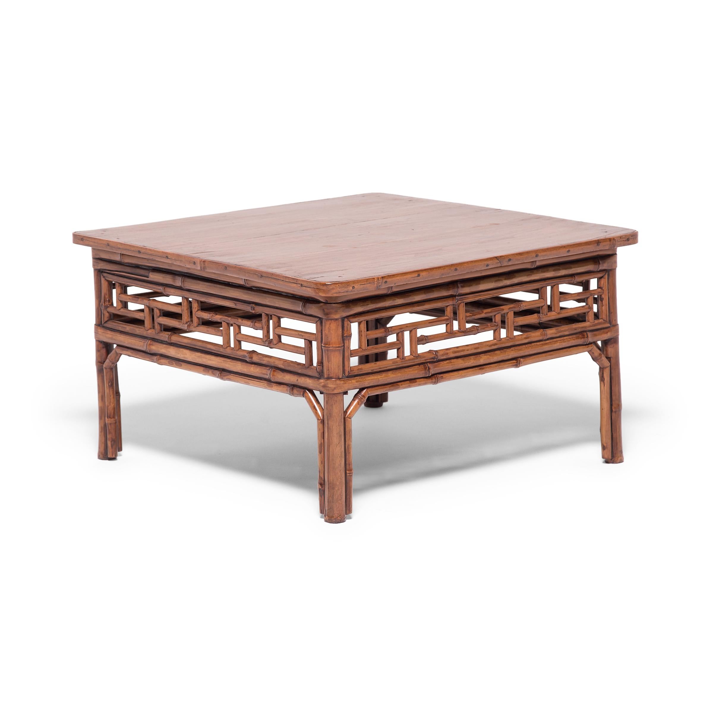 This 19th century low square table from southern China is built from spotted bamboo. It is brilliantly constructed with a geometric fretwork apron and legs held in place with double wraparound stretchers. Creating furniture from bamboo was a