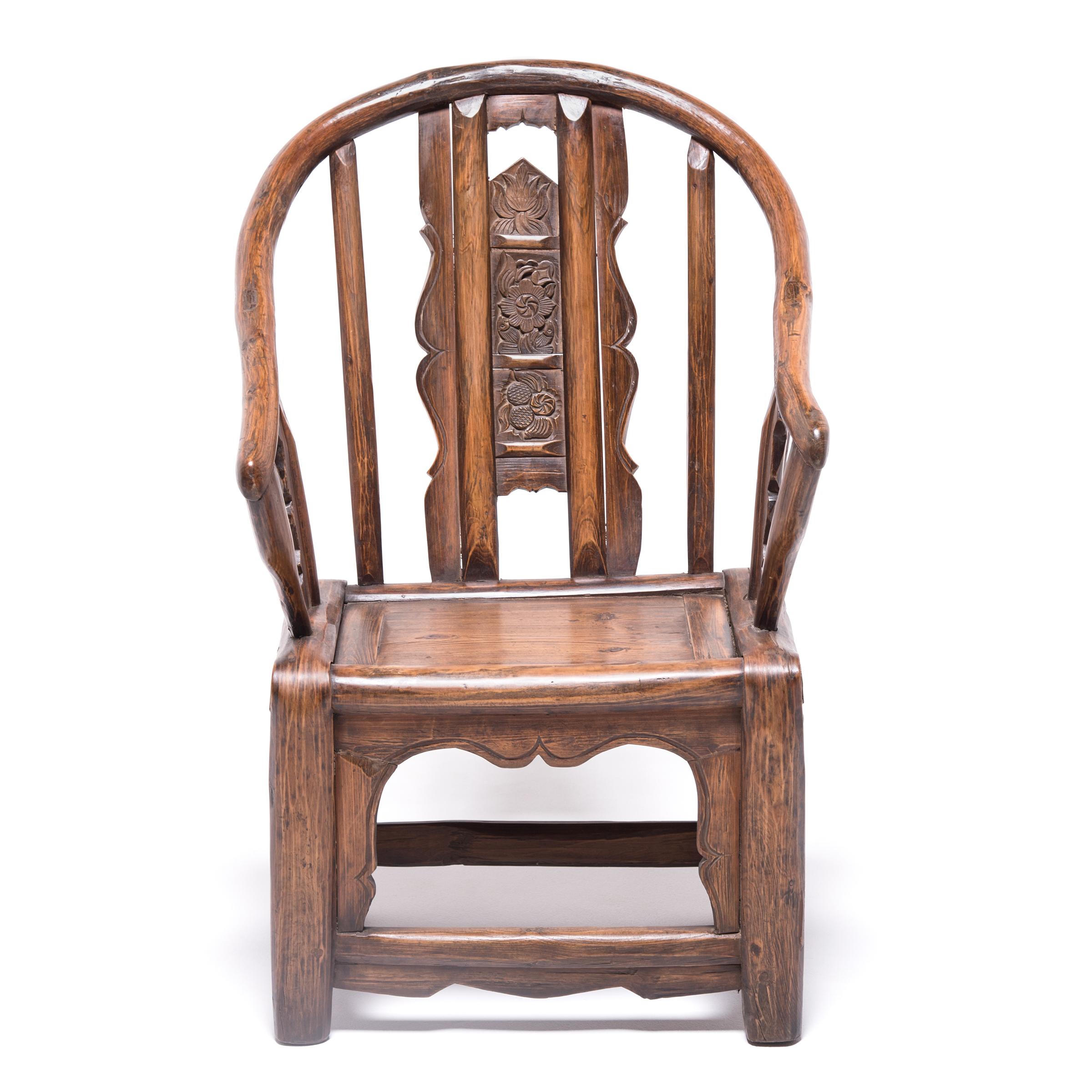 This bentwood chair was created over a century ago in northern China by moistening, bending, and heating willow to form its desired shape. It is beautifully carved with auspicious flowers and is considerably smaller than most roundback chairs. As