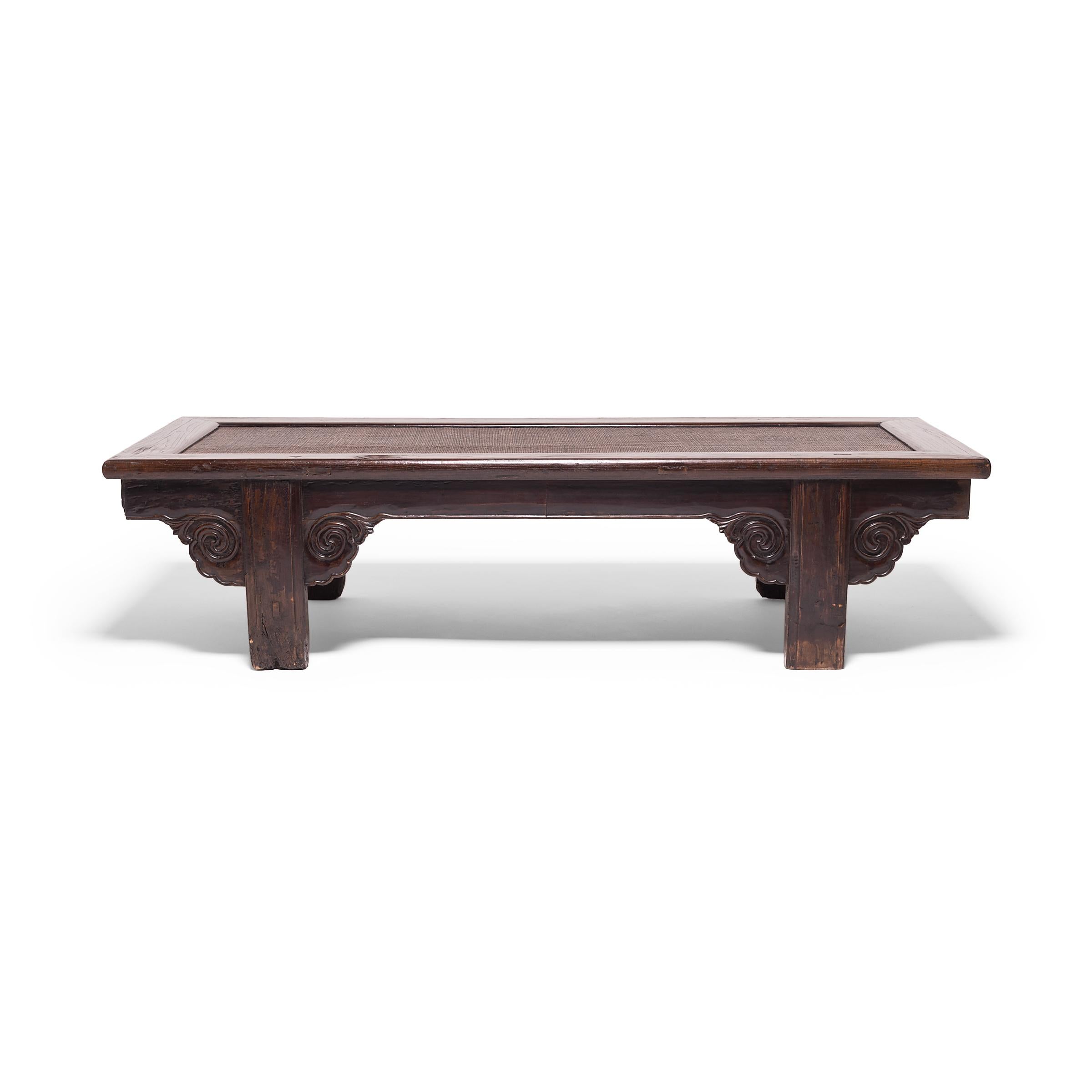 This handsome table is a prime example of traditional Chinese craftsmanship. The frame of the beautifully worn top is lined with a finely woven mat, carved clouds form spandrels on the apron, and the mortise and tenon joinery lend the piece an