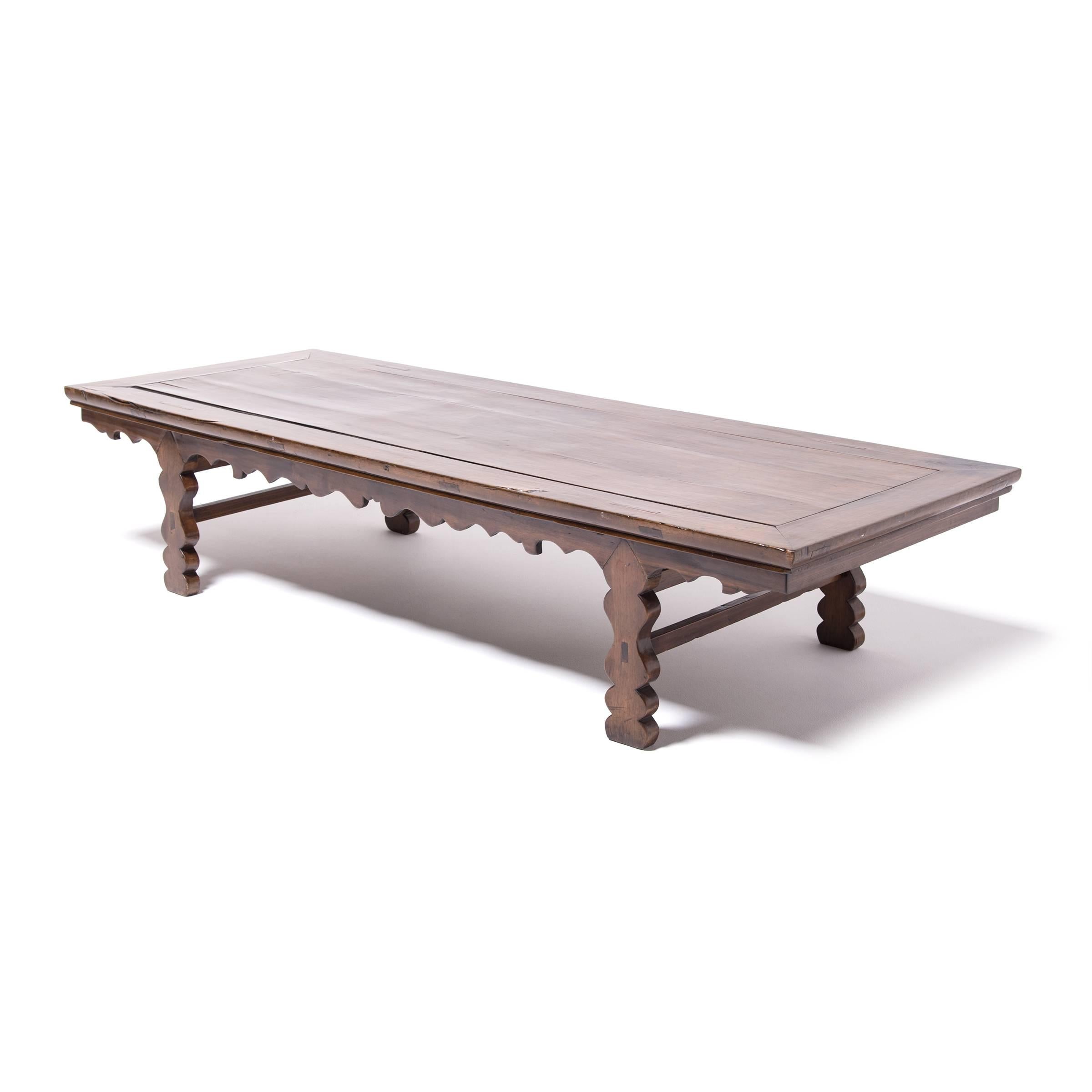 Made of warm toned walnut, this 19th century low table streamlines the meandering vine motif seen in traditional Chinese scrollwork in a dramatically curved apron and legs. Its low profile calls attention to the floating panel top. Appearing in many