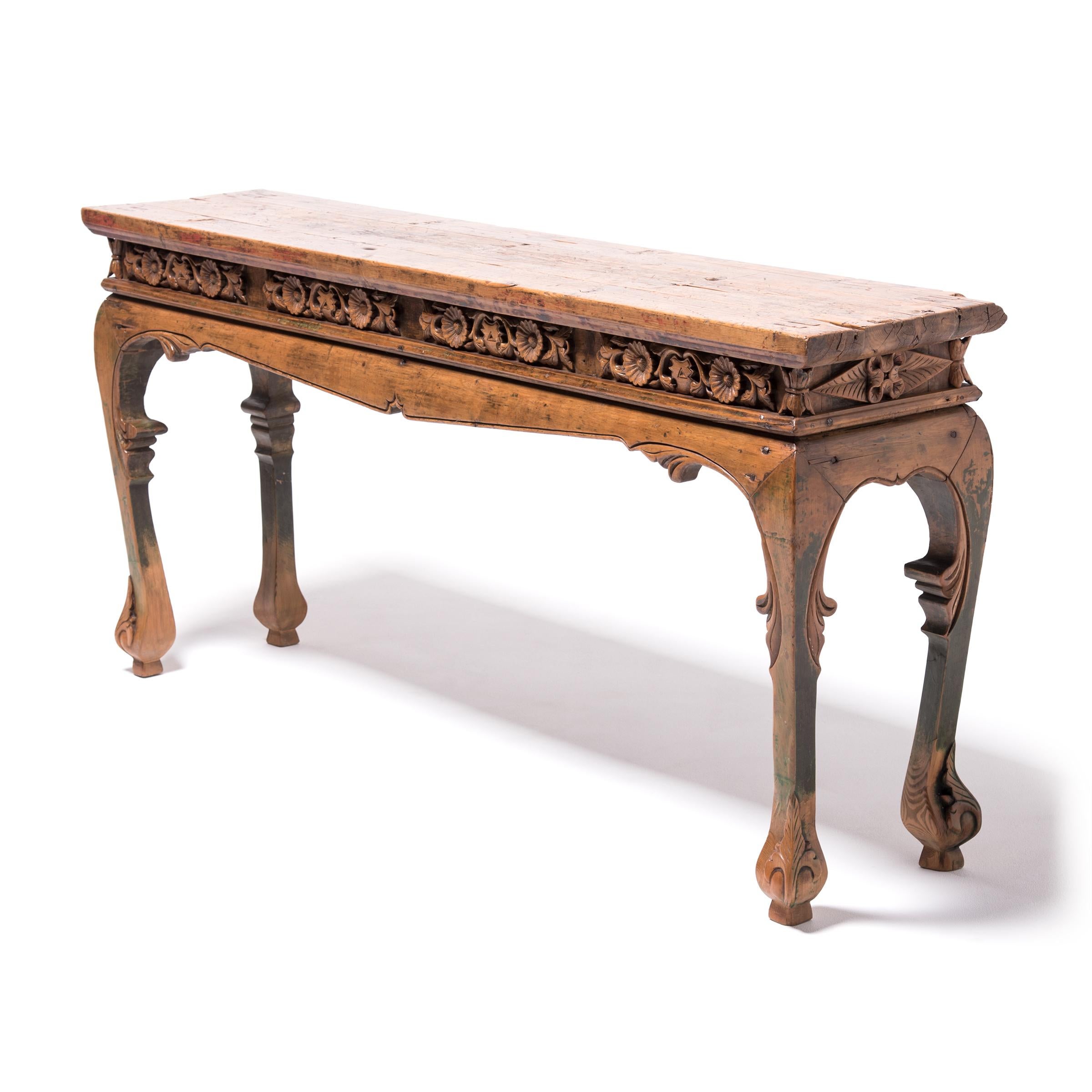 Cultivated in all parts of China, the chrysanthemum is esteemed for its variety of forms and rich colors. This favored flower is carved in a graceful repeat motif on the apron of this exquisitely crafted 19th century pine wood table, complemented by
