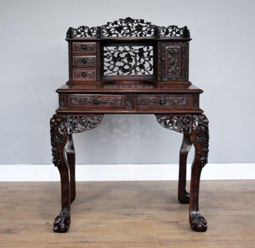 For sale is a good quality 19th century carved Padouk wood desk, having a row of small drawers, and a rectangular door enclosing stationery divisions, projecting base with drawers to frieze, pierced and carved throughout with blossoming prunus,