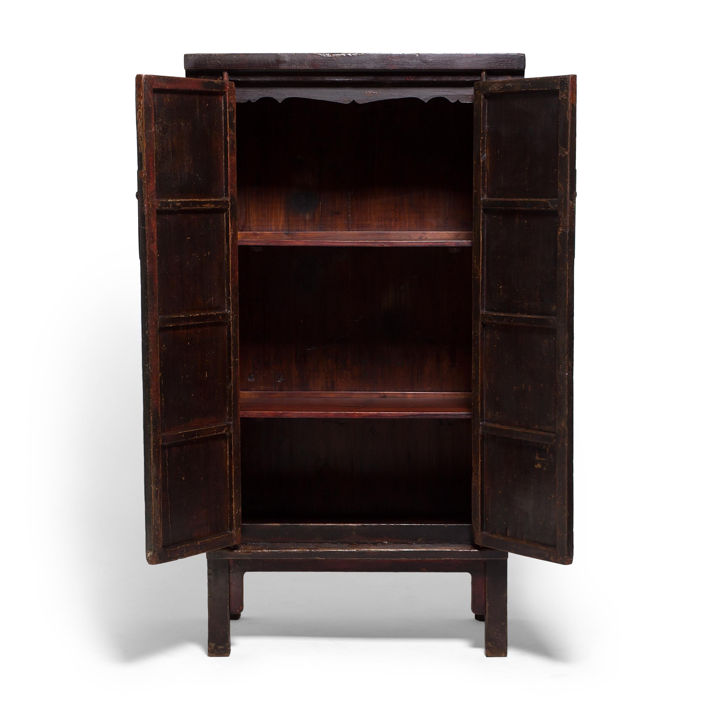 Evincing the austere attitude of Ming-dynasty aesthetics, this 19th century cabinet is minimally accented with clean lines, rounded spandrels, and discrete brass hardware. Traces of the original painted decoration adorn the tall doors, depicting a