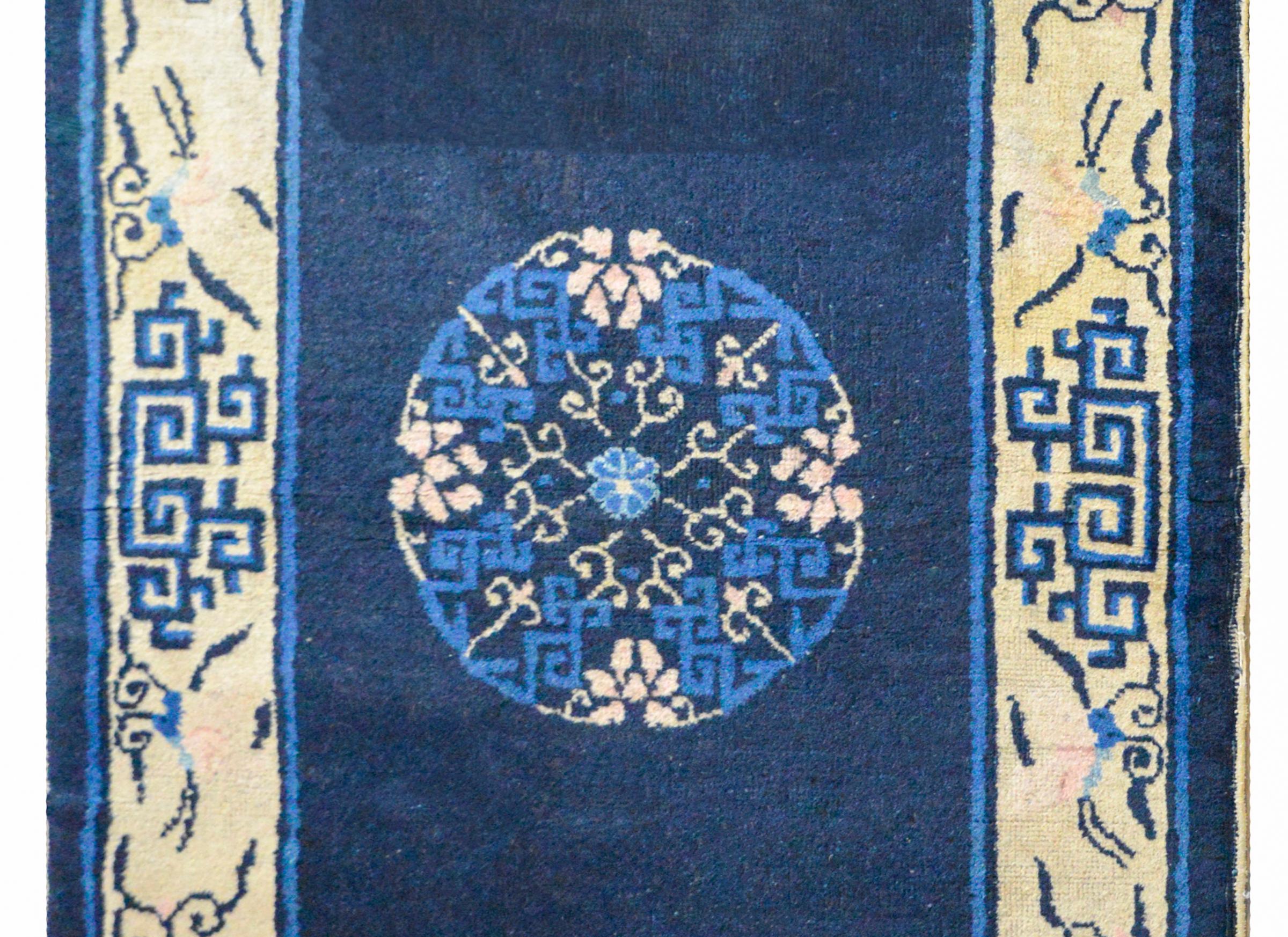 A beautiful 20th century Chinese Peking rug with a central floral medallion against a dark abrash indigo background, and surrounded by a wide stylized lotus and scrolling vine pattern. The field is abrash, meaning the variation in colors is