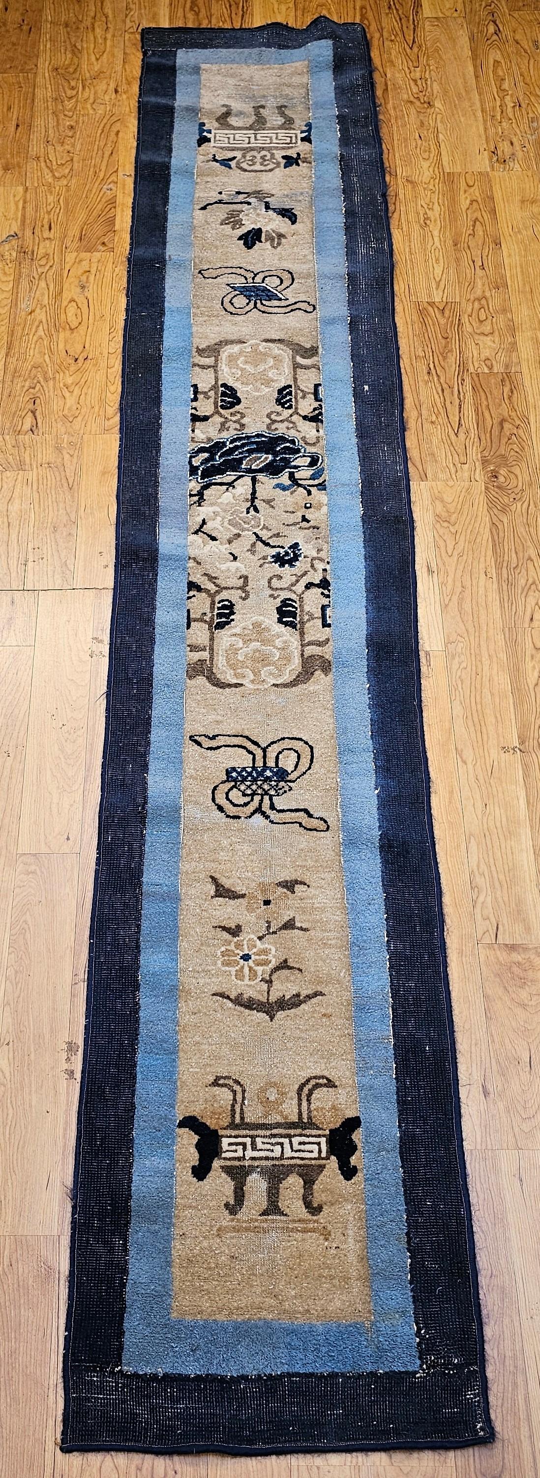 This elegant 19th century Chinese Peking runner is a rare and refined hand knotted rug that embodies the subtle beauty of traditional Chinese design. Woven in soft tones of ivory, navy, and baby blue, the rug features a column of symbolic motifs