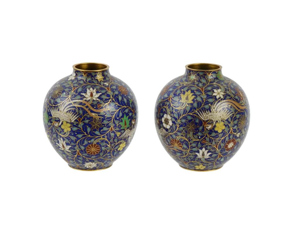 A pair of 19th century Chinese, Qing Dynasty, globular shaped enamel vases with wide necks. The vase are adorned with polychrome enamel Phoenix bird, floral, and foliage ornaments on the cobalt blue ground made in the Cloisonne technique. Unmarked.