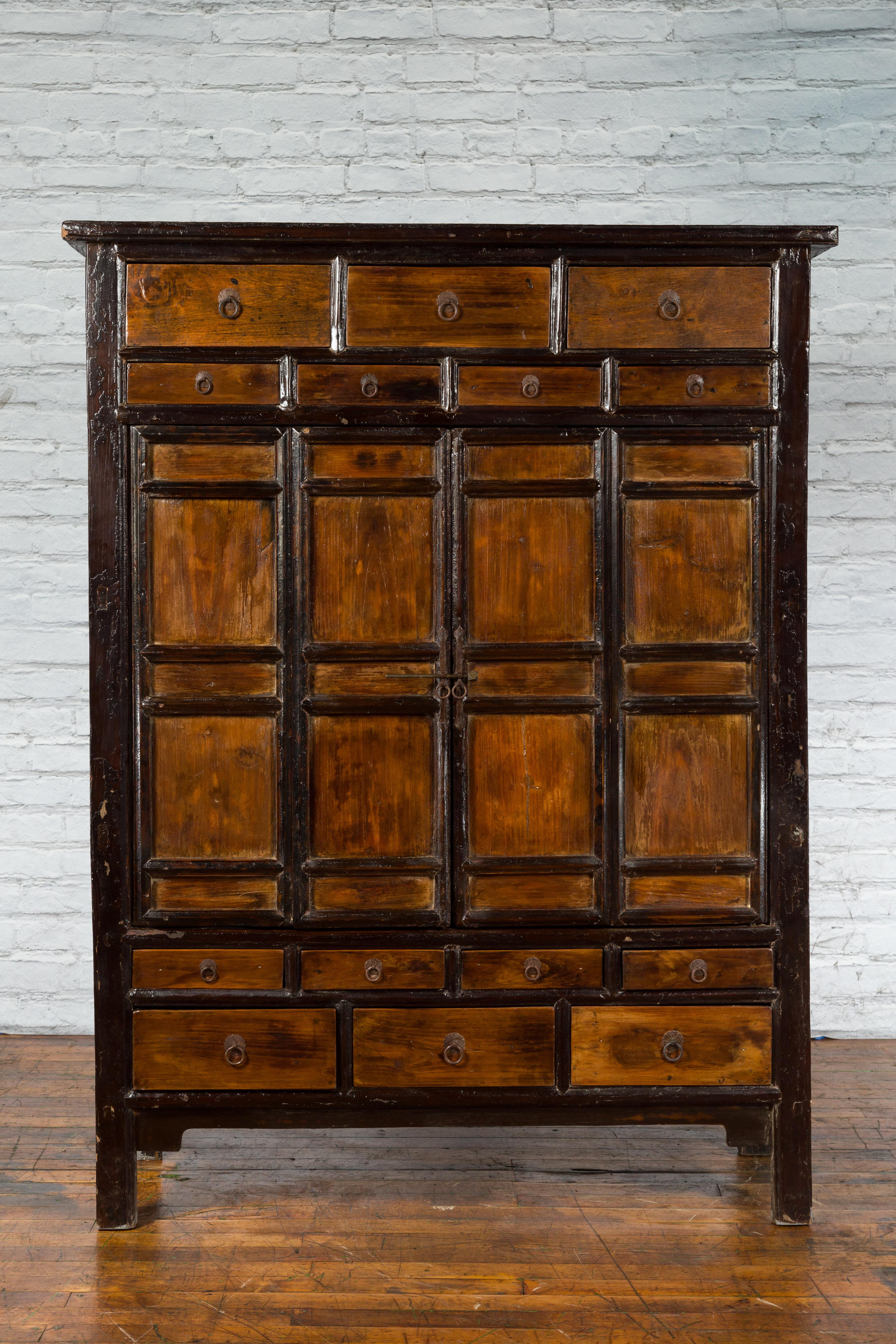 A large Chinese Qing Dynasty period armoire cabinet from the early 20th century with 14 drawers and two accordion doors. Created in China during Qing Dynasty in the early years of the 20th century, this cabinet attracts our attention with its