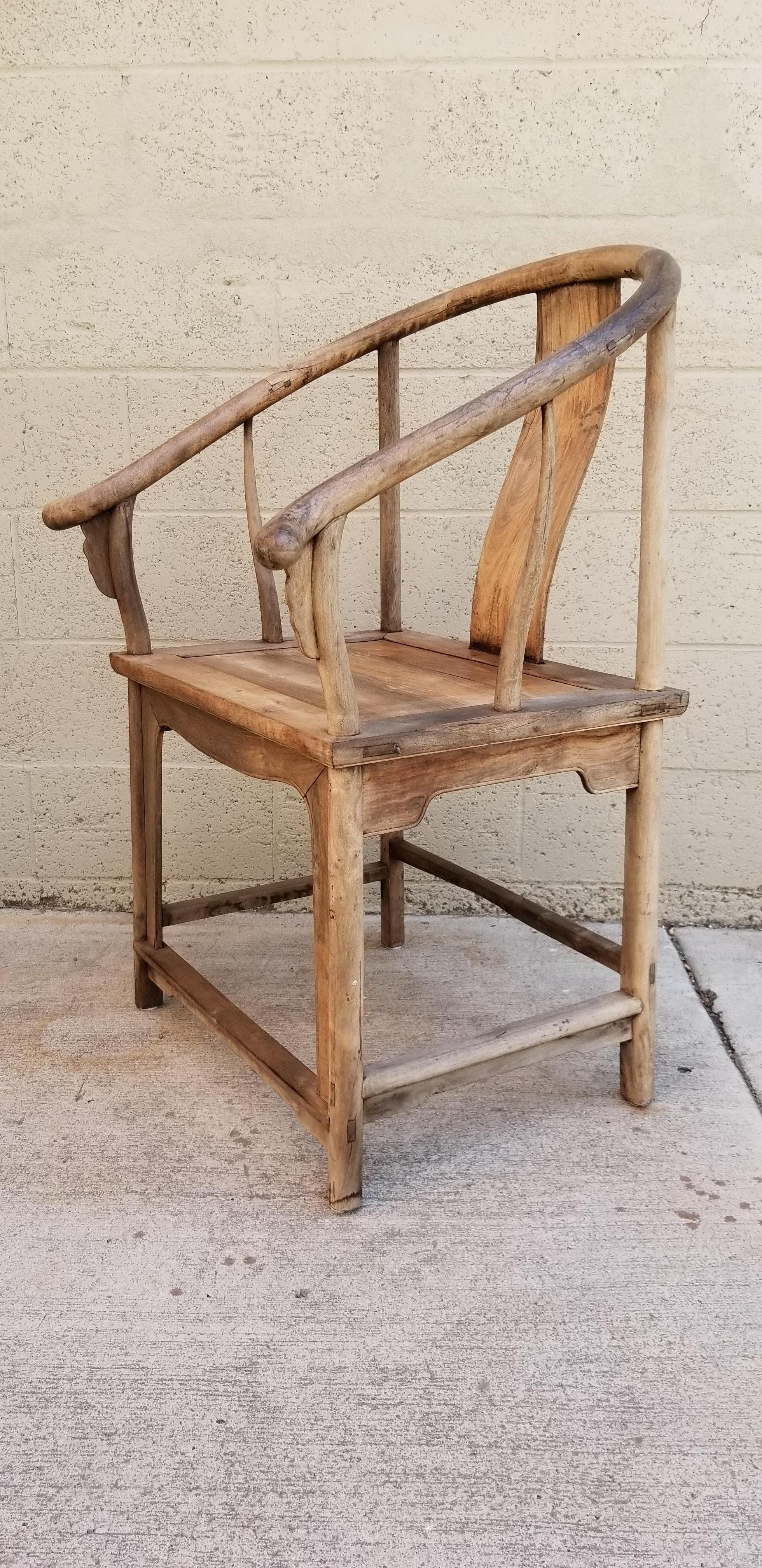 A late 1800s Chinese horseshoe chair made of a hardwood that appears to be walnut or teak. Old-World weathered finish give this chair wonderful, unique character. Plank seat, intricate joinery, graceful arms.
