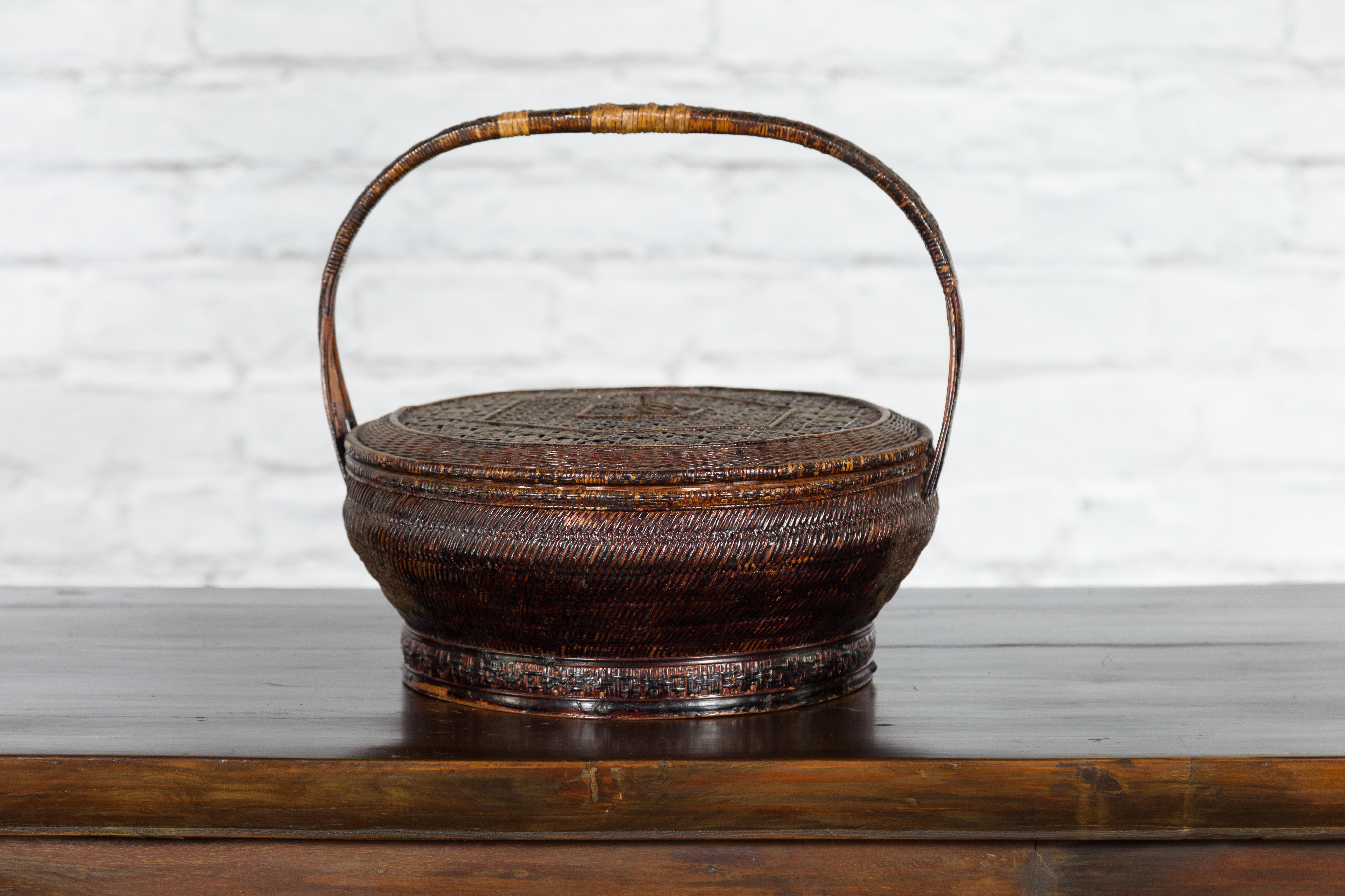 A small Chinese Qing Dynasty period basket from the 19th century hand-woven with rattan on a bamboo armature. Created in China during the Qing Dynasty, this rustic basket features a circular top adorned with hexagonal concentric motifs, surrounding