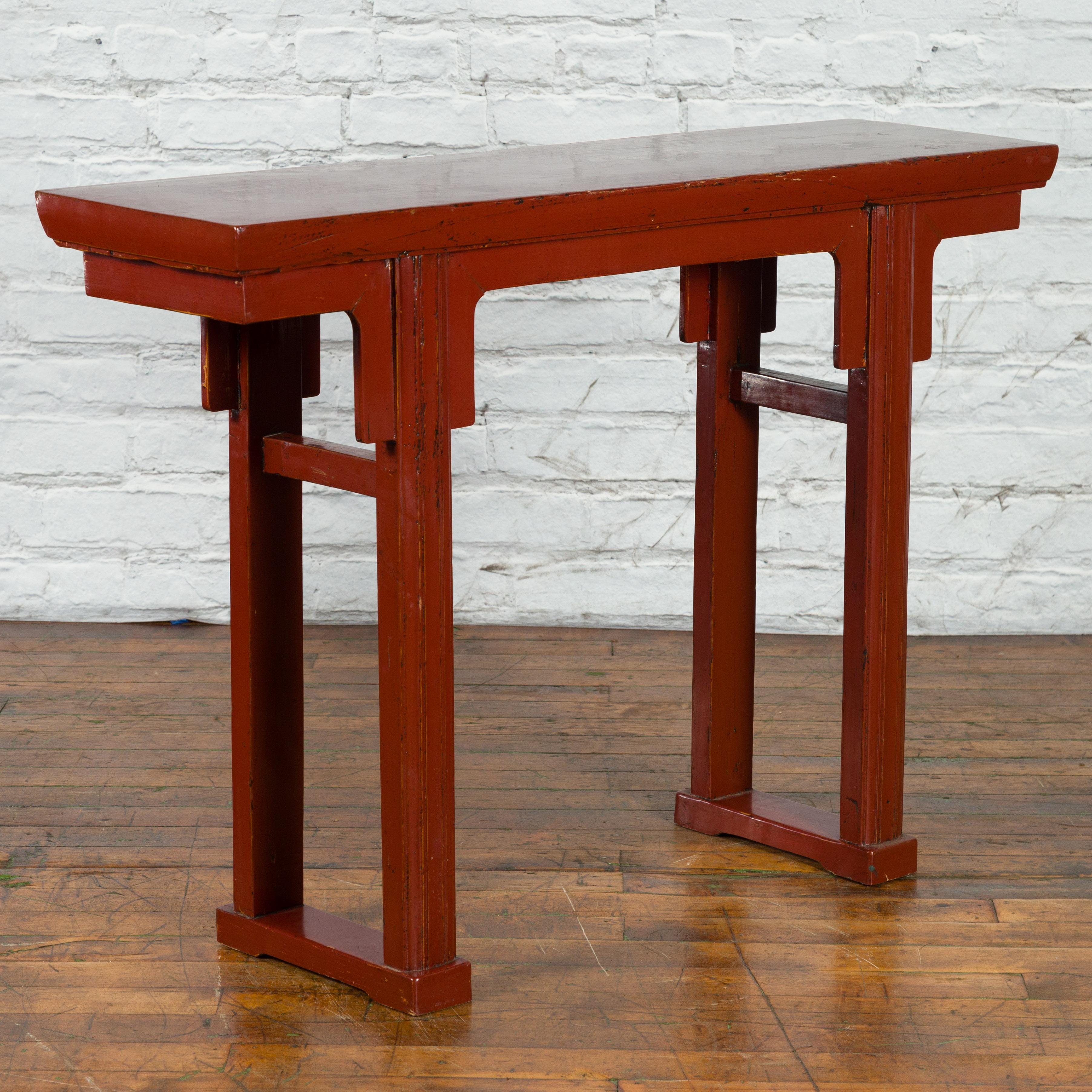 A Chinese Qing Dynasty period elmwood altar console table from the 19th century, with red lacquer and carved apron. Created in China during the Qing Dynasty, this elmwood console table features a rectangular top sitting above a simply carved apron.