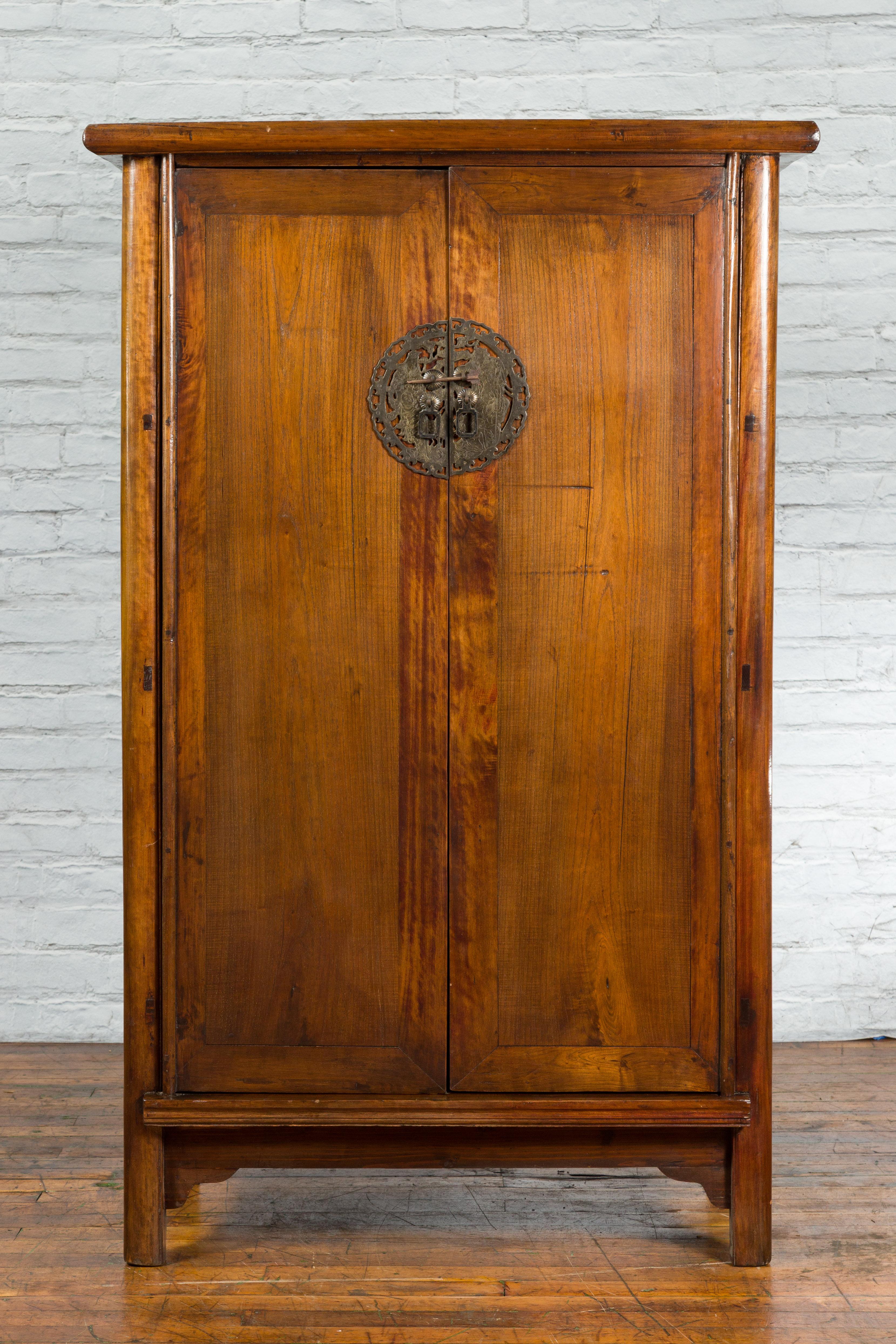 A Chinese Qing Dynasty period cabinet from the 19th century, with large bronze etched medallion. Created in China during the Qing Dynasty, this 19th century cabinet features a rectangular top overhanging two doors flanked with rounded side posts and