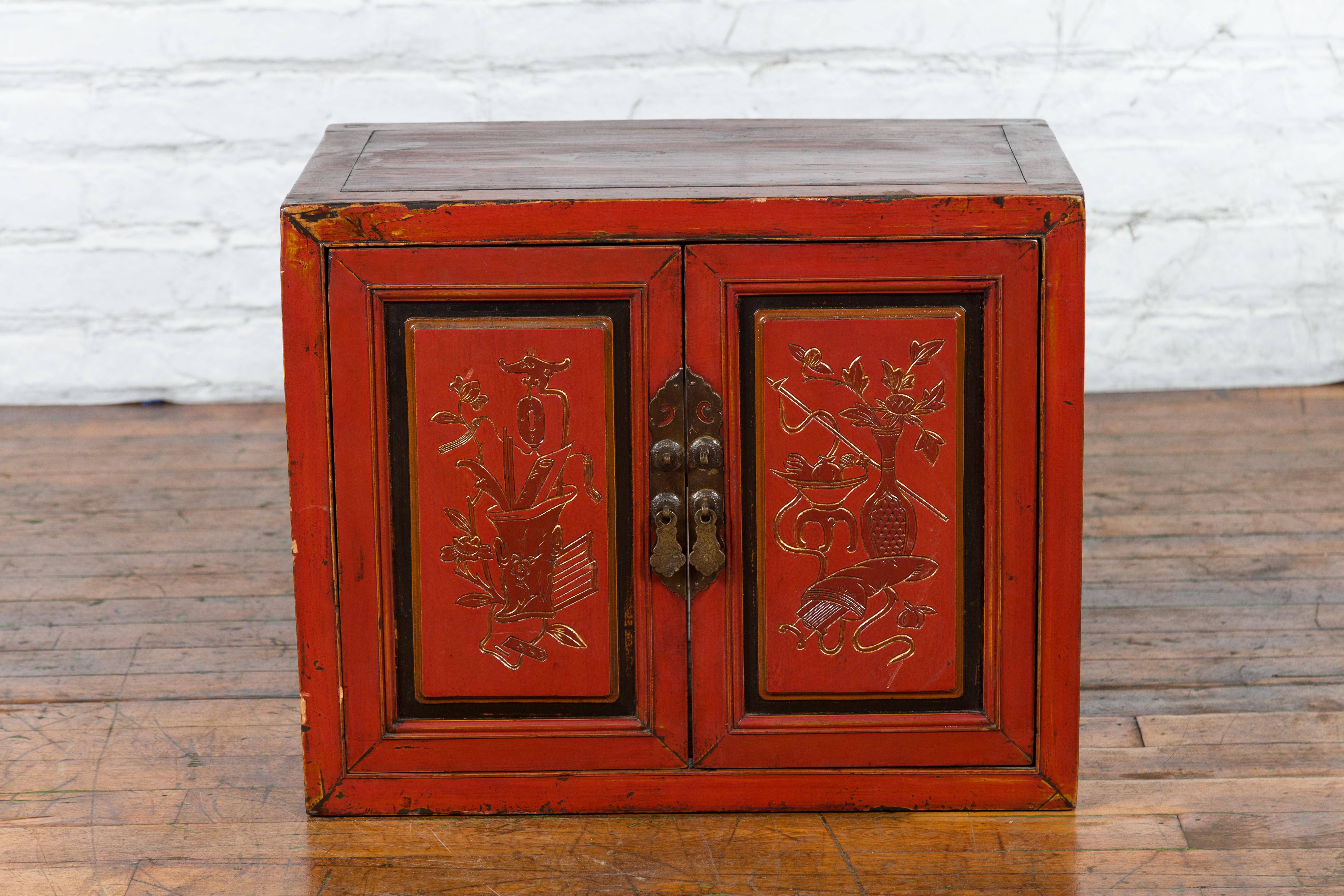 A Chinese Qing Dynasty period red lacquer cabinet from the 19th century, with hand-carved doors. Created in China during the Qing Dynasty, this cabinet features a traditional linear shape perfectly complimented by a red lacquer with some black