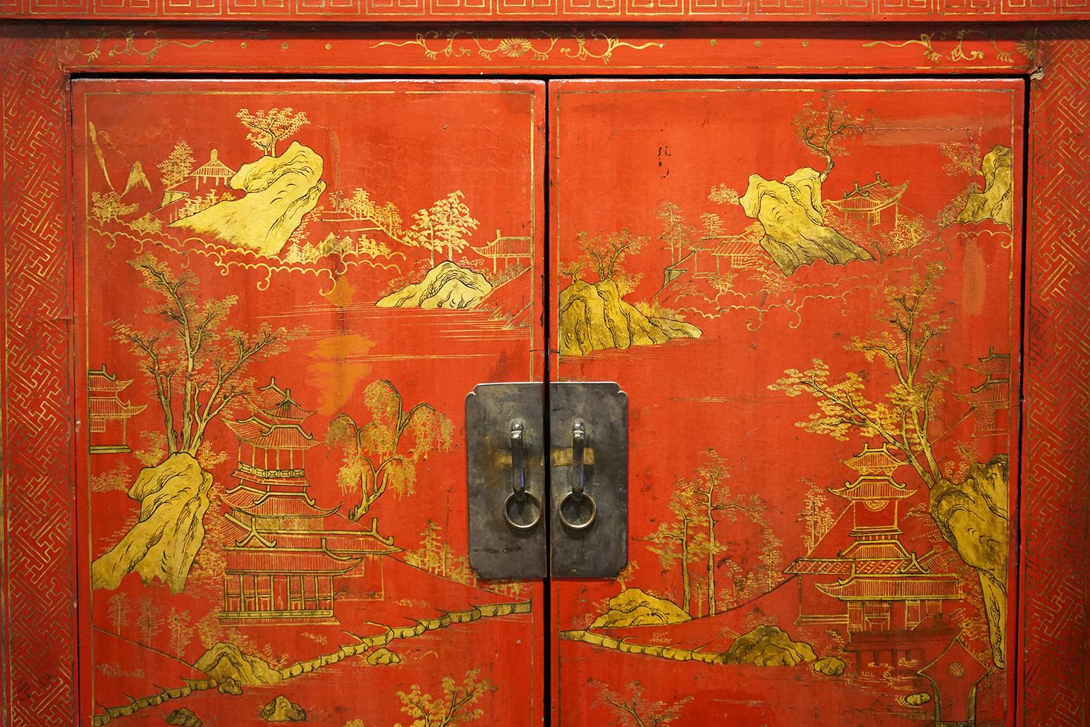 This late 19th century red lacquer and gilt decoration two door wedding cabinet has a wonderful warm patina. The doors are decorated with rocky landscapes, trees, temples and birds. The side panels are decorated with more formal cartouches. The