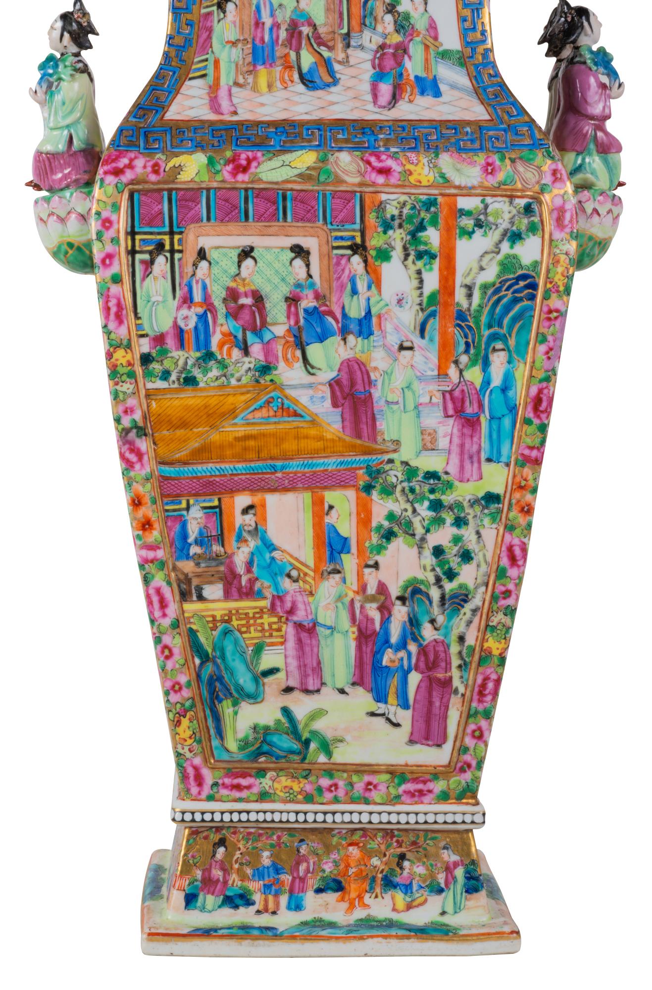 A wonderful late 19th century Chinese Cantonese (Rose Medallion) lidded vase, having bold classical colors, figural handles on either side and to the lids, inset hand painted panels depicting male and female courtiers promenading around gardens and