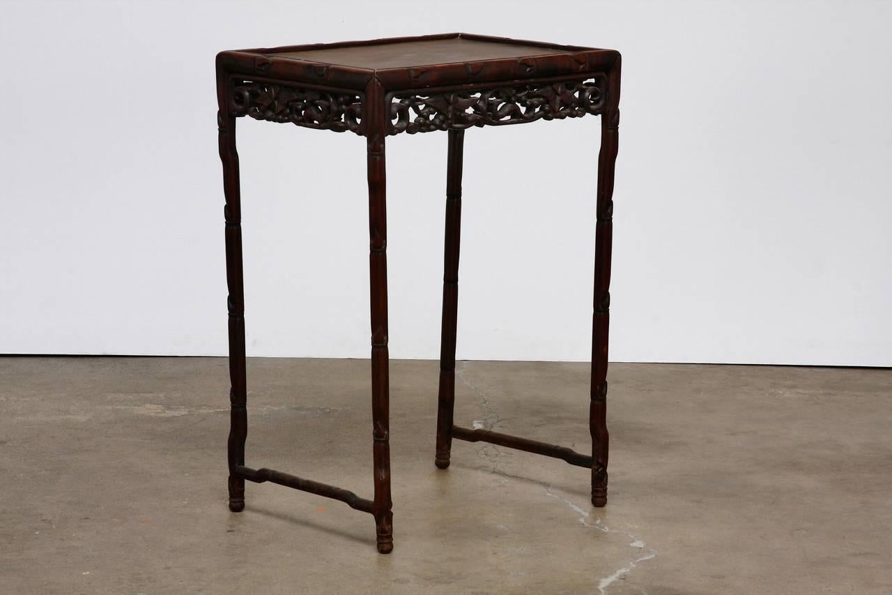 Stunning 19th century Chinese carved rosewood tea table or side table featuring an intricate pierced frieze on all four sides. Supported by delicate faux bamboo motif legs joined by a hump back stretcher. The table appears to have had three